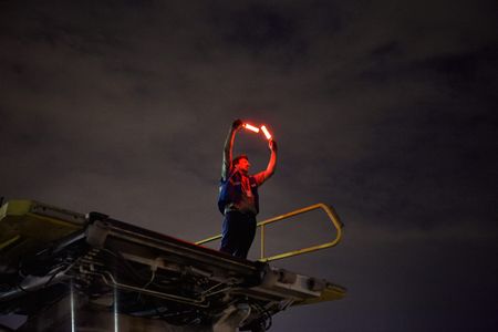 Air Marshaling a airplane at night time, as he stands up high on a lift so that the pilots in the cockpit of the 747 can view him properly. The air Marshal is wearing a protective vest and shot from belwo as he guides the aircraft with his two red safety wands. Next stop, the other side of the world! This was a project shooting for the air cargo transportation industry. This project was amazing as an industrial photographer, on location photographer & location commercial photographer. Shot with shallow depth of field and selective focus. Air Marshal Guiding an Aircraft
