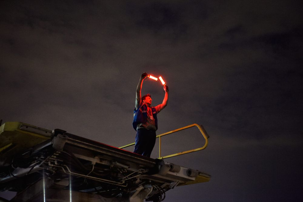 Air Marshaling a airplane at night time, as he stands up high on a lift so that the pilots in the cockpit of the 747 can view him properly. The air Marshal is wearing a protective vest and shot from belwo as he guides the aircraft with his two red safety wands. Next stop, the other side of the world! This was a project shooting for the air cargo transportation industry. This project was amazing as an industrial photographer, on location photographer & location commercial photographer. Shot with shallow depth of field and selective focus. Air Marshal Guiding an Aircraft
