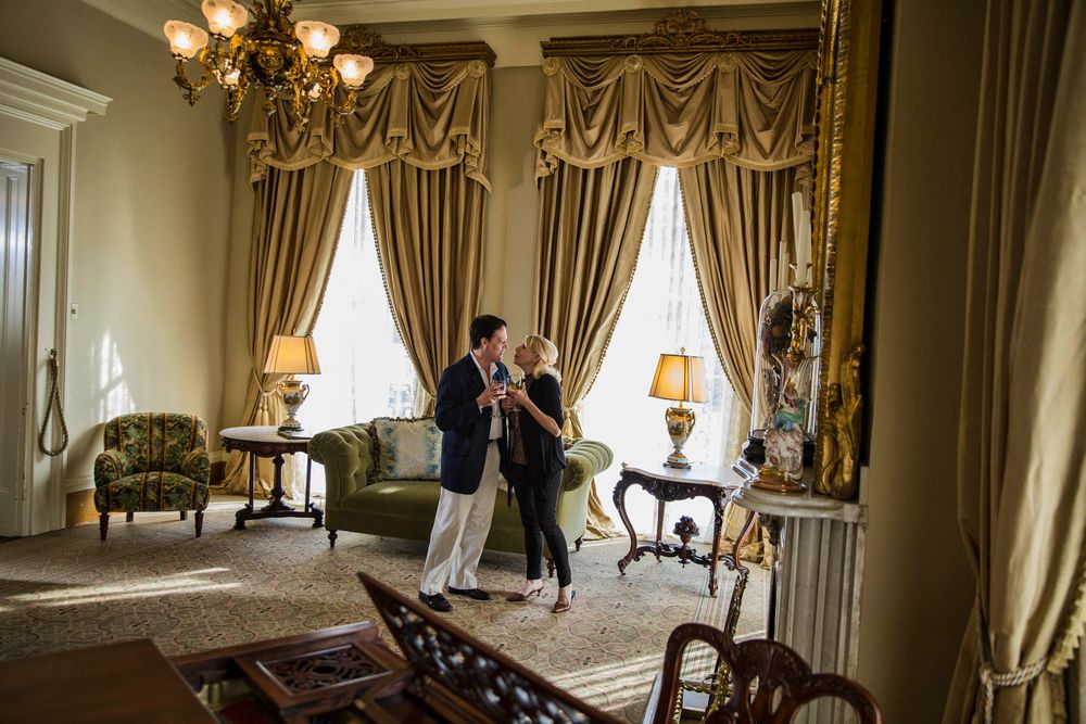 Wide photo of a middle age loving couple inside a large beautiful, plantation style home, being affectionate and holding drinks in nice light. Shot for the Mississippi Tourism campaign for advertising, branding, collateral and broadcast motion assets. Environmental portrait, and we are a industrial photographer, on location photographer & location commercial photographer. VisitMS Couple Large Plantation Living Room