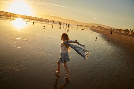 A young girl, with a scarf blowing in the wind, running on the beach in Venice, CA. Photo made at sunset. Girl on Beach