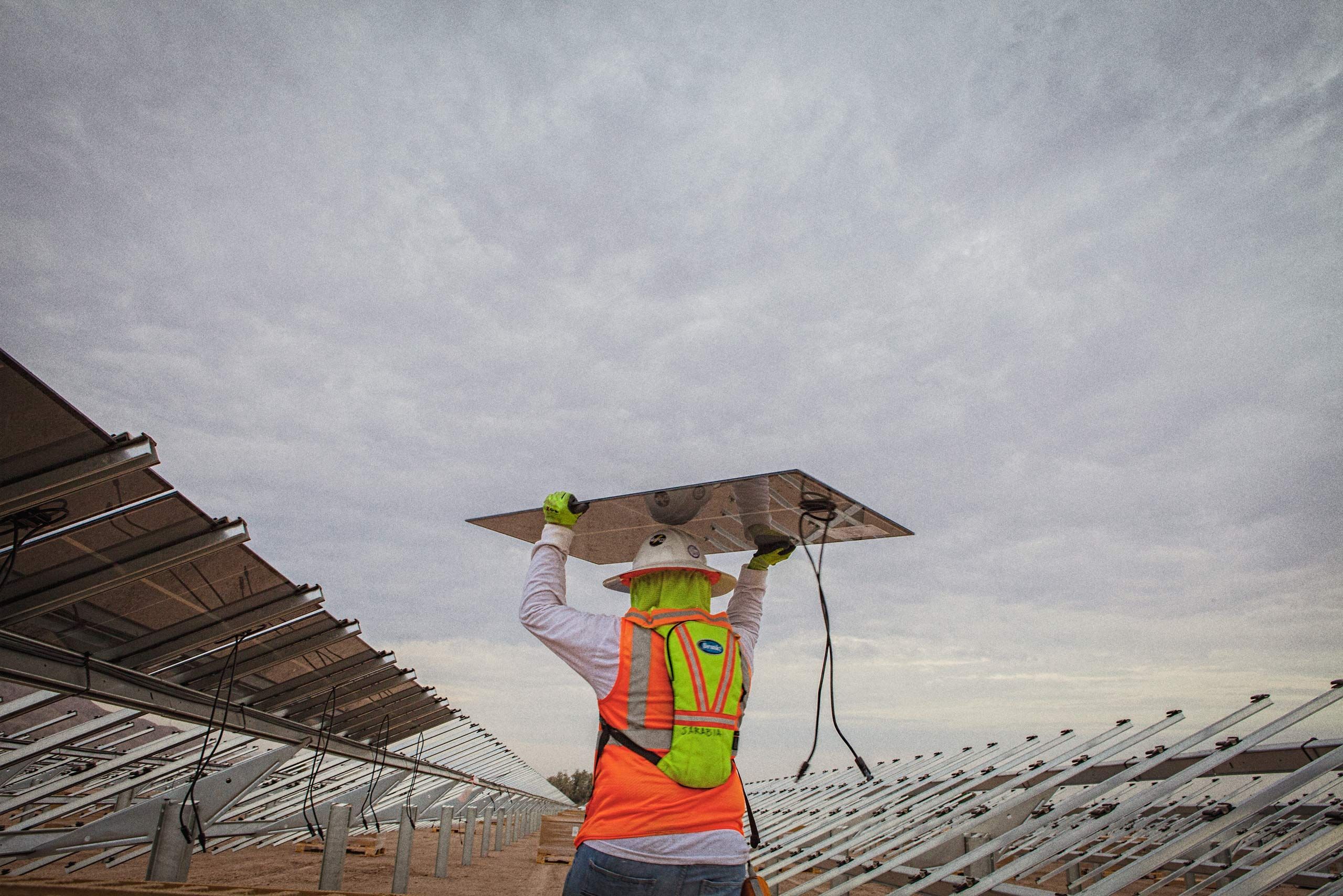 Worker Walking Holding a Solar Panel Over His Head