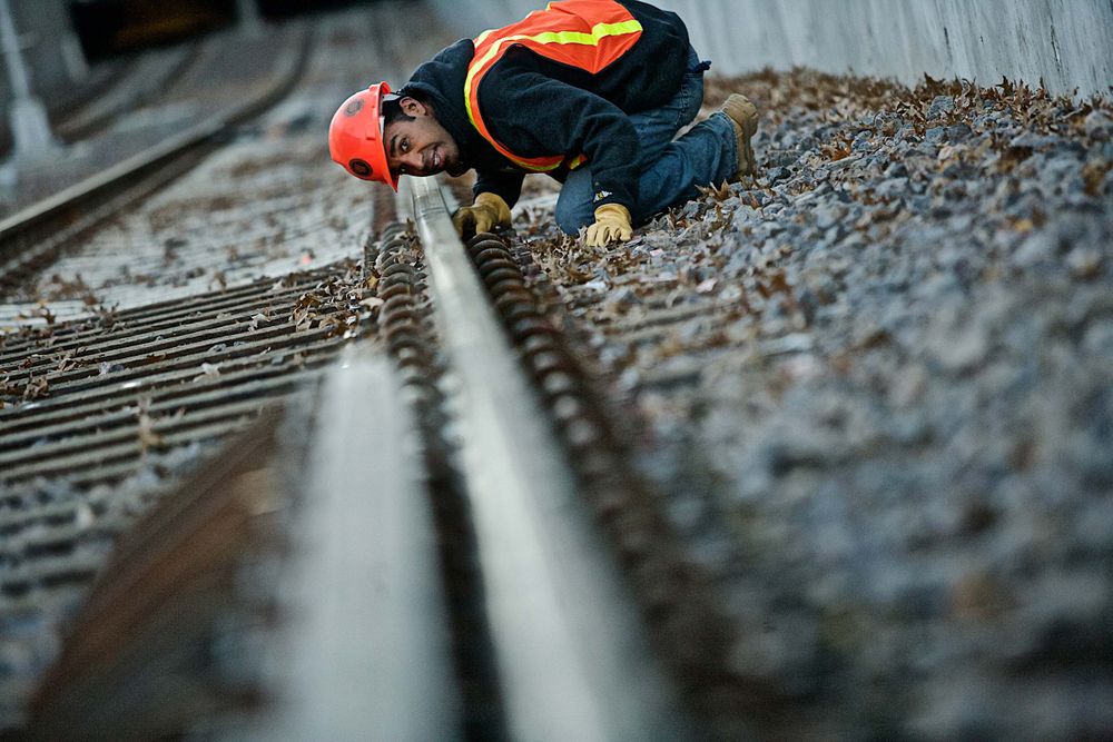A man, engineer, from a low angle, long lens, shallow depth of field. He is inspecting the installation of a new rail system in St. Louis. Man Inspecting a Railroad