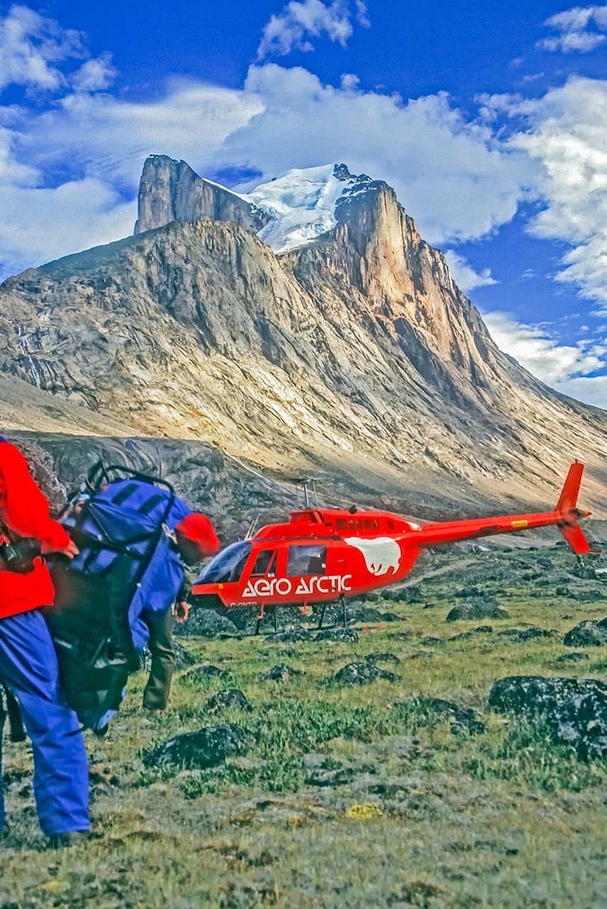 Breidablik Peak to the rear is in Auyuittuq National Park and near Mt. Asgard and Mt. Thor. An injured climber being evacuated, Baffin Island, Canada.