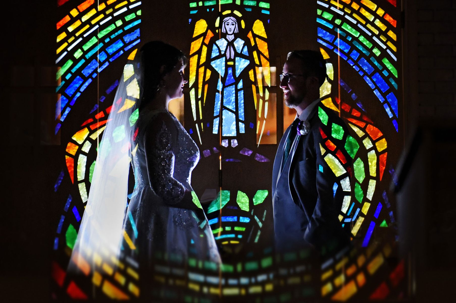 Bride and groom reflection in stained glass church window Creative wedding photography in Chicago