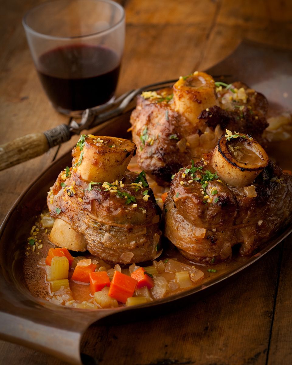 www.rkjacobs.comGiada De Laurentiis Osso Buco with vegetables on rustic table with red wine Robert Jacobs Photography ©2013 Top Food Photographer New York Seattle Portland