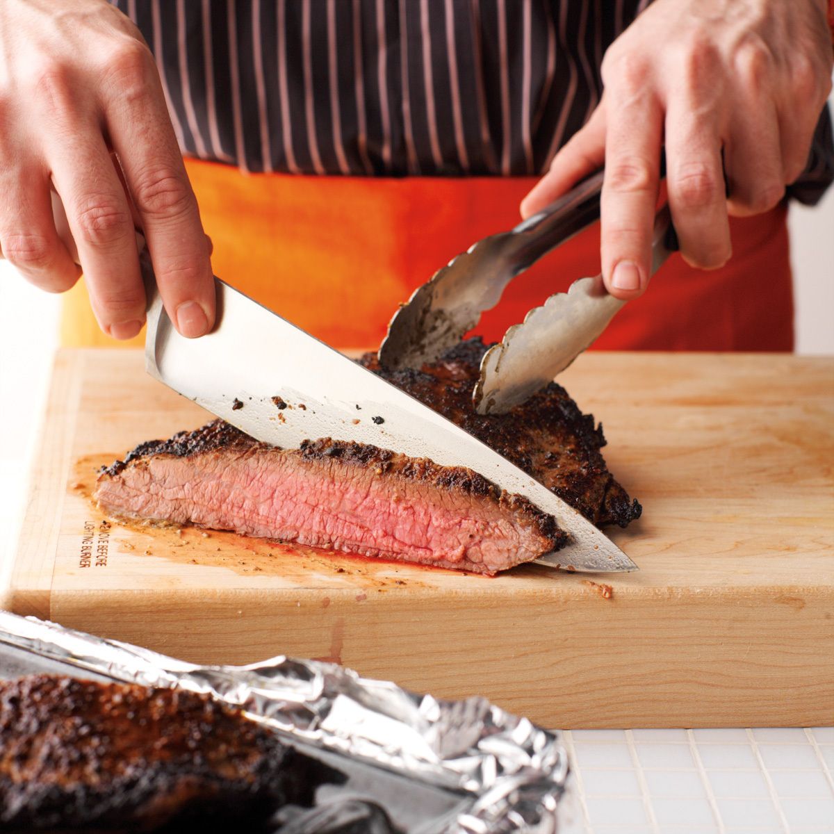 Man slicing london broil steak on wooden cutting board, Food Network Kitchens "How to Boil Water" cookbookslicing steak 0002 www.rkjacobs.comTop Food Photographer New York Seattle PortlandRobert Jacobs Photography ©2013 Man slicing london broil steak on wooden cutting board, Food Network Kitchens "How to Boil Water" cookbookwww.rkjacobs.comTop Food Photographer New York Seattle PortlandRobert Jacobs Photography ©2013