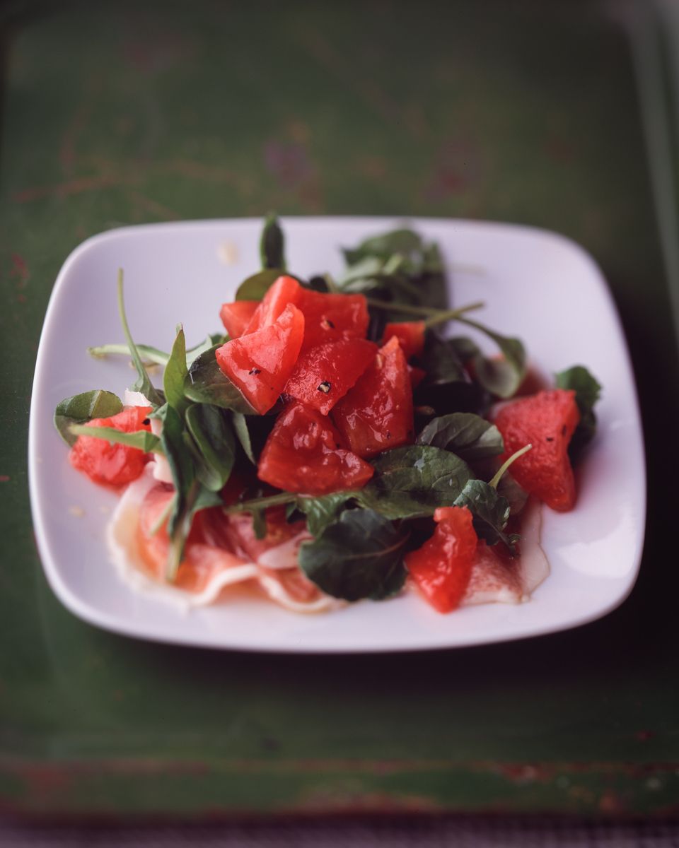 prosciutto with tomatoes, arugula, on white plate on green surface  www.rkjacobs.comtop food photographer New York Seattle Portland Robert Jacobs photography ©2013