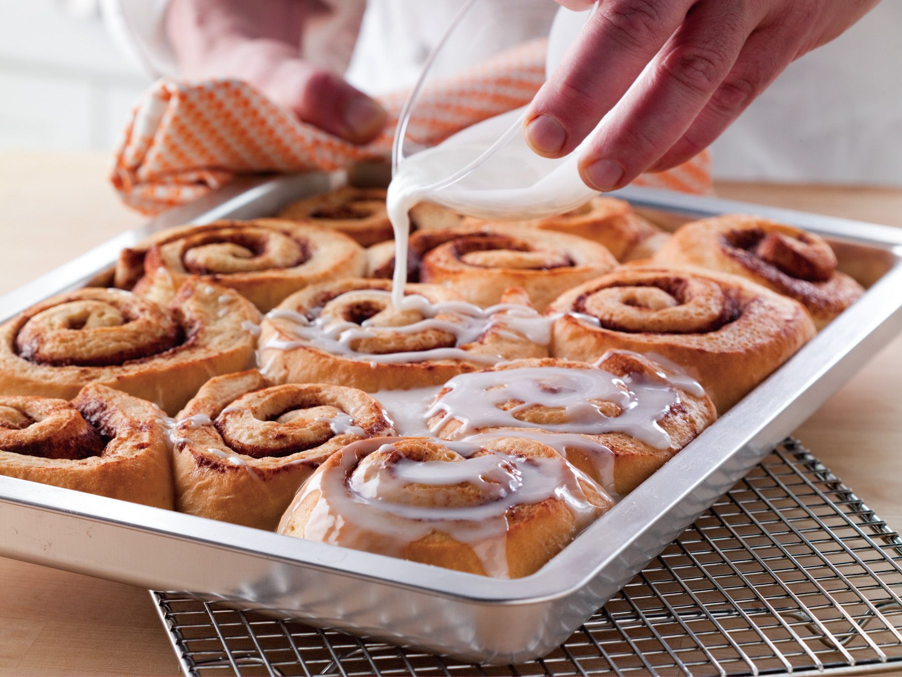 Tray of Cinnamon Rolls with hand pouring frosting over rollswww.rkjacobs.comFood NetworkTop Food Photographer New York Seattle PortlandRobert Jacobs Photography ©2013 Tray of Cinnamon Rolls with hand pouring frosting over rollswww.rkjacobs.com   Food NetworkTop Food Photographer New York Seattle PortlandRobert Jacobs Photography ©2013