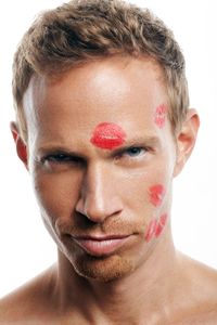 Male model and actor with lipstick kisses on face