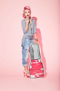 Photo of Influencer and make up artist Kandee Johnson with oversized nail polish cut out on pink background