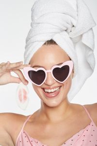 Model showing lipstick color removal swipe with bath towel on head and pink heart shaped sunglasses for brand 