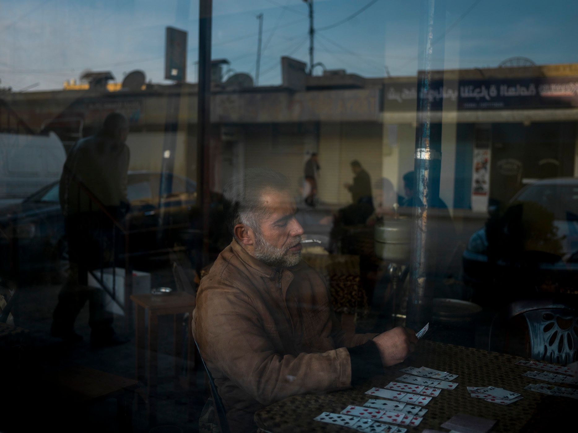 Man smoking and playing a game of cards in a cafe in central Qamishlou. 16.jpg