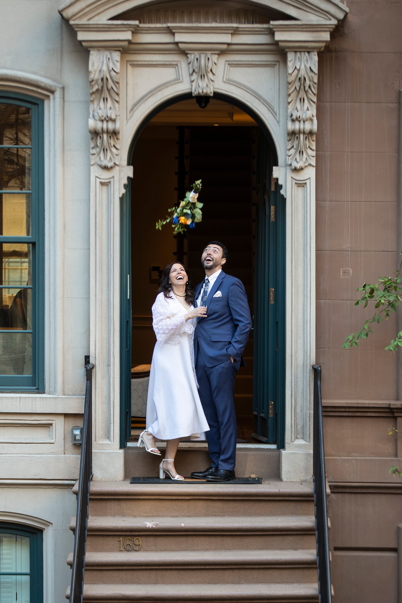 Bride and groom tossing bouquet on NYC townhouse steps