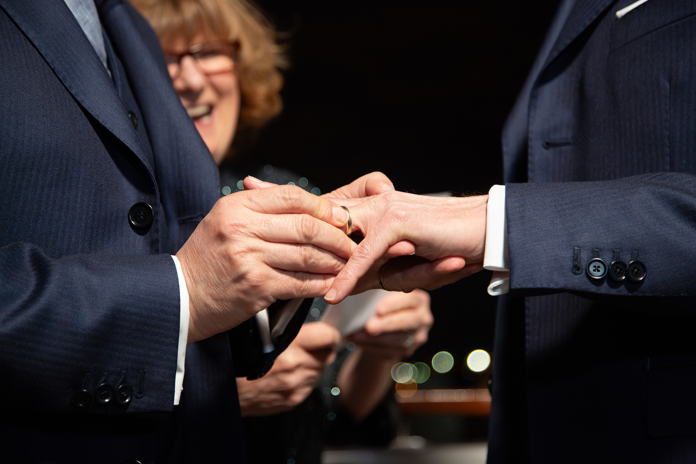 Close‑up of groom placing ring on partner’s hand