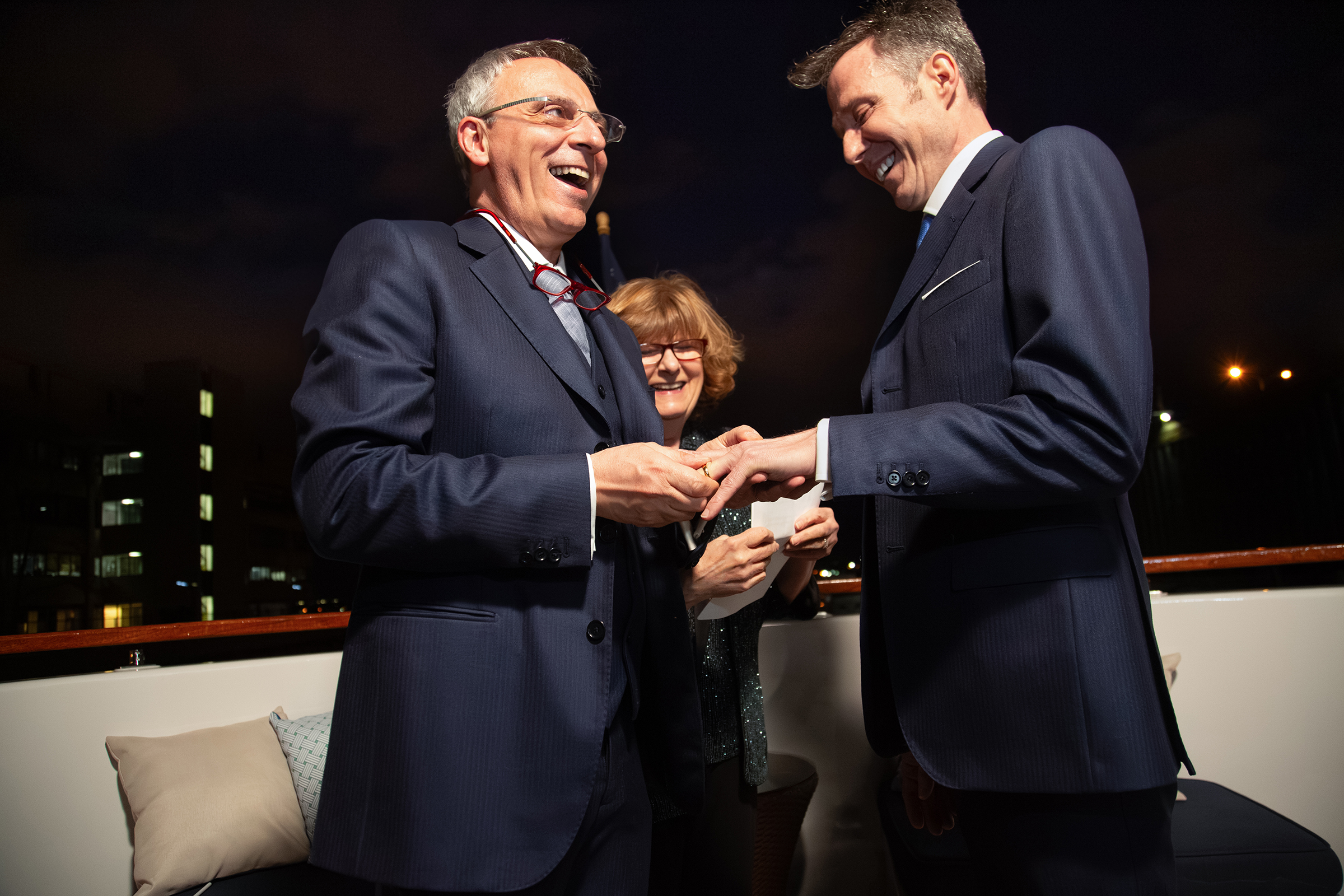 Grooms exchange rings during dusk wedding on Hudson River yach