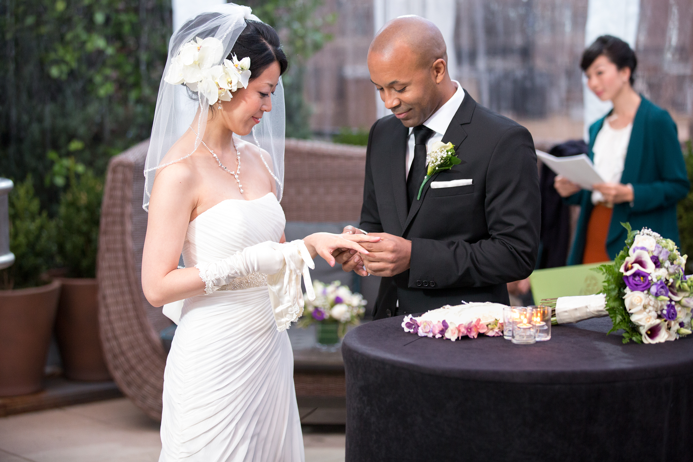 Groom placing ring on bride’s hand at rooftop wedding ceremony