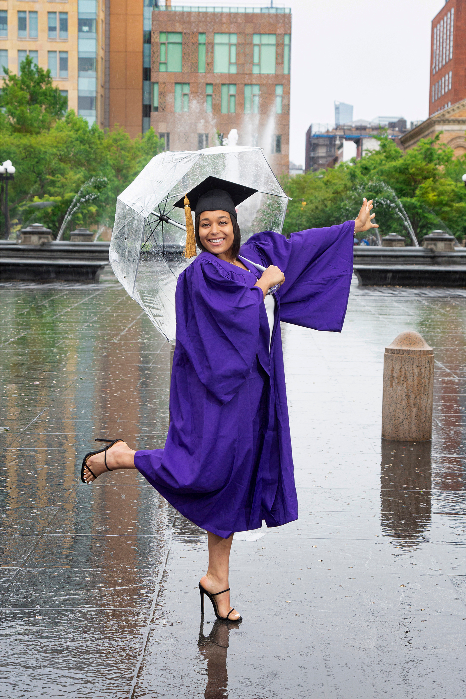 NYU graduate dancing with clear umbrella in the rain