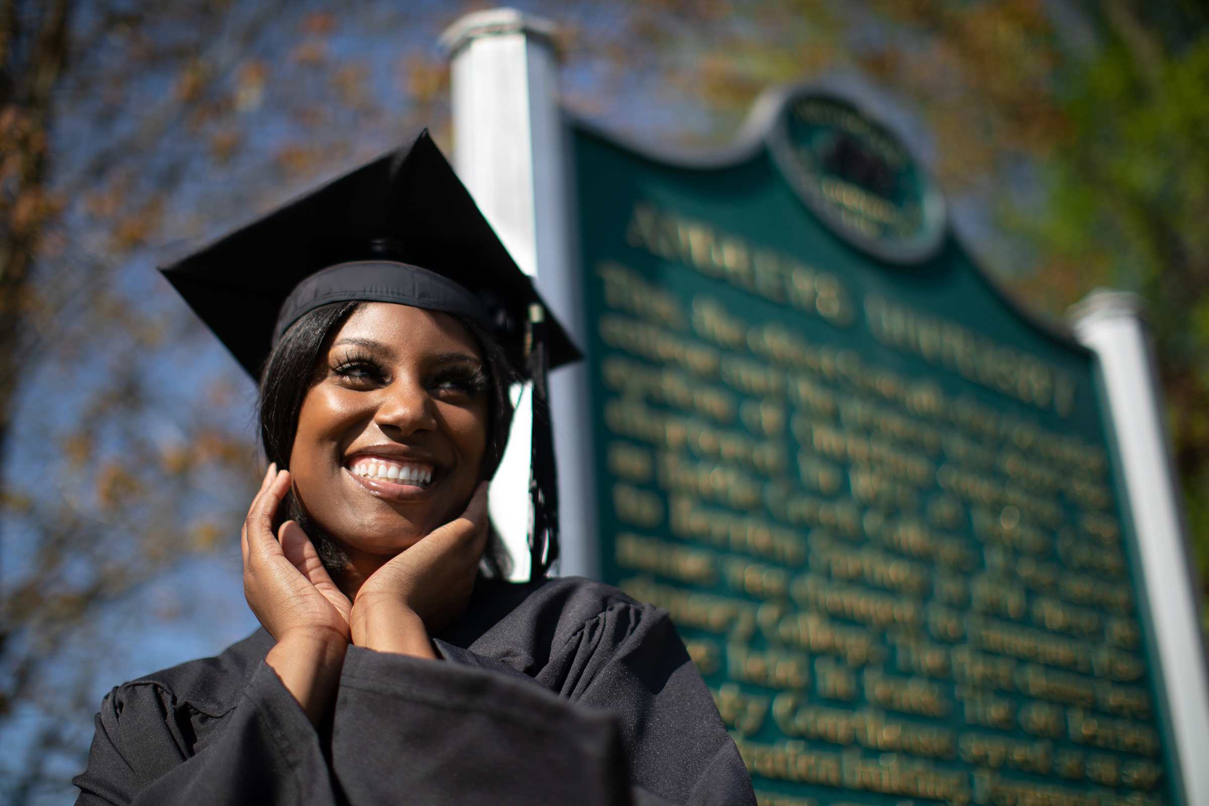 Laughing Black graduate in front of Andrews University plaque
