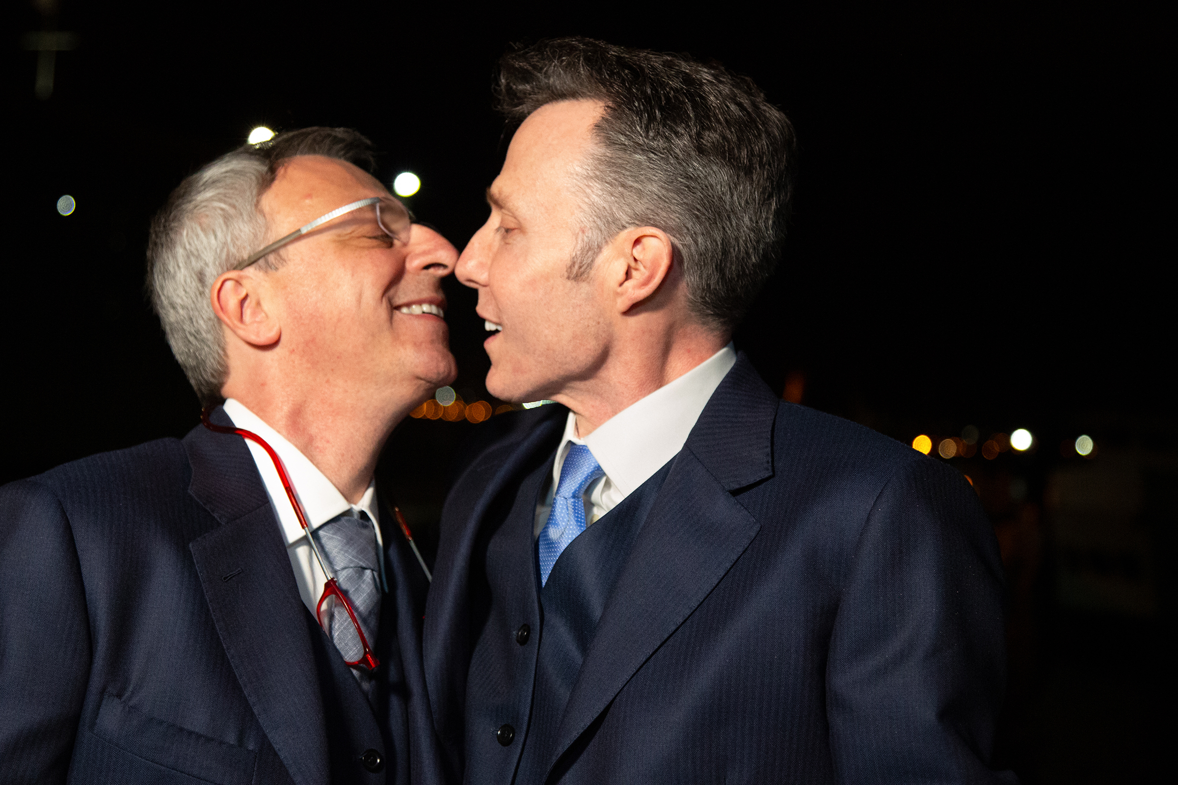 Grooms smiling after first kiss during nighttime yacht wedding