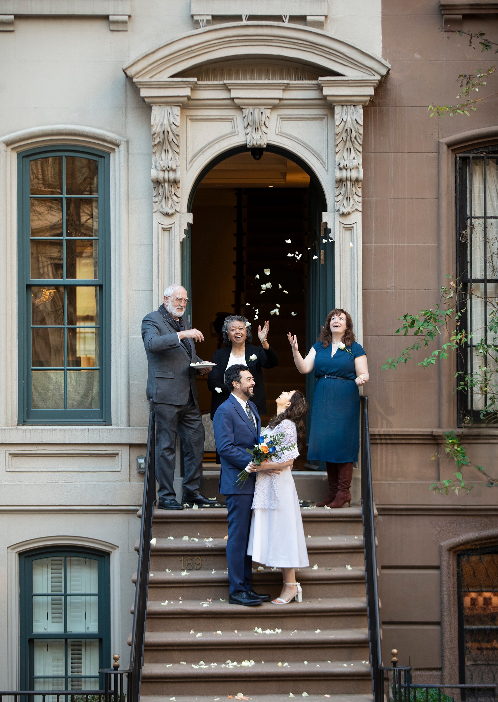 Bride and groom on NYC townhouse steps with petals