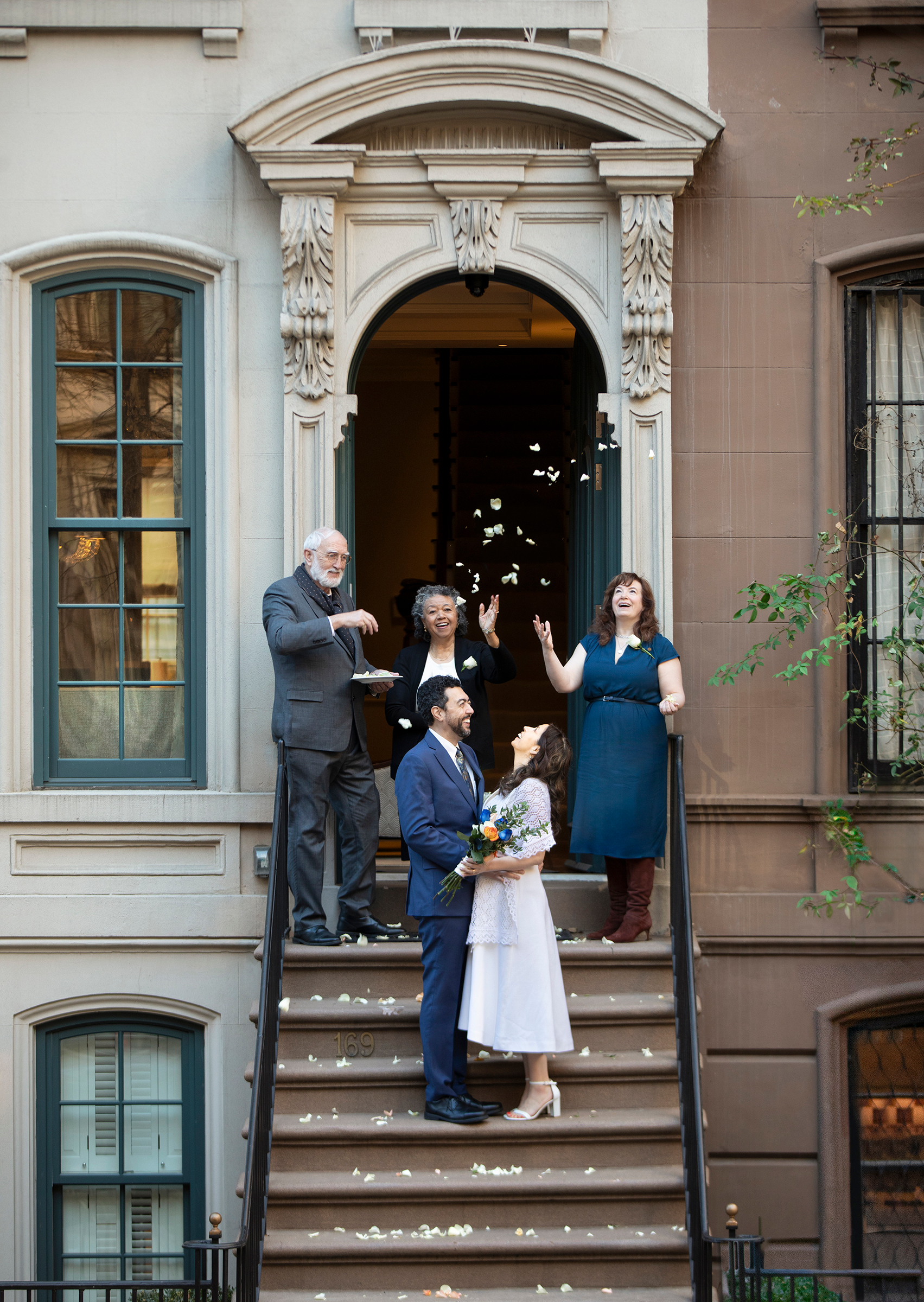 Bride and groom on NYC townhouse steps with petals