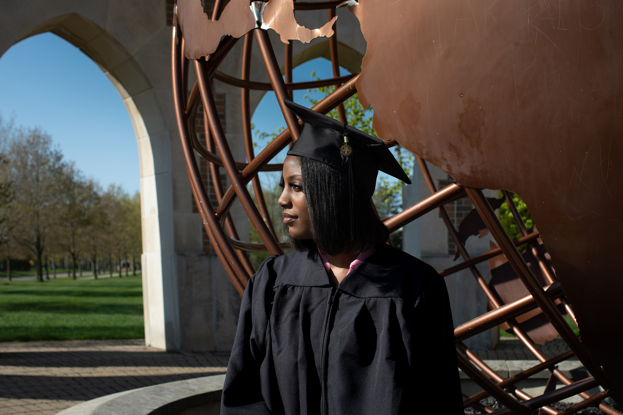 lack graduate in cap and gown at Andrews University globe