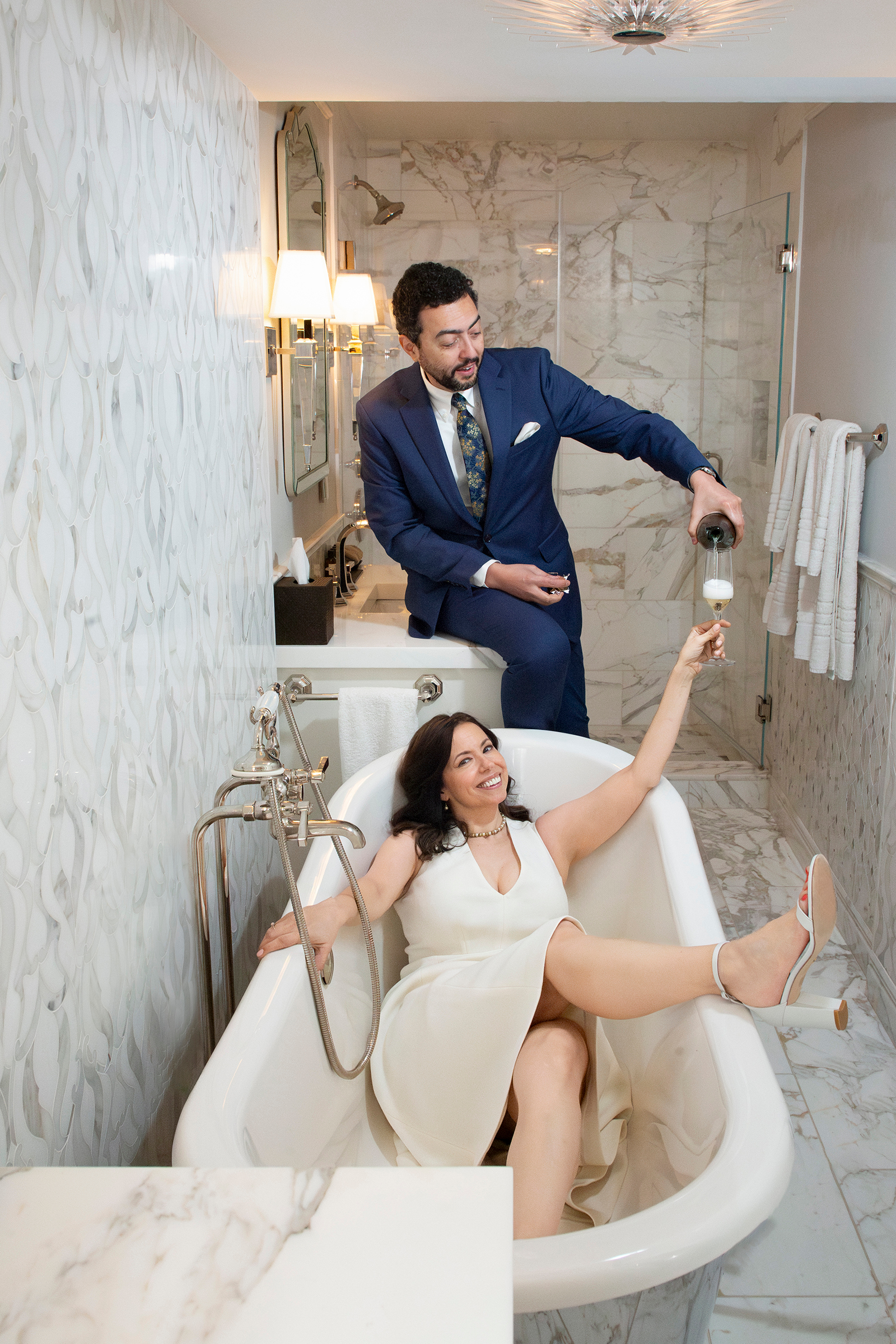 Bride in bathtub with champagne in marble bathroom wedding portrait