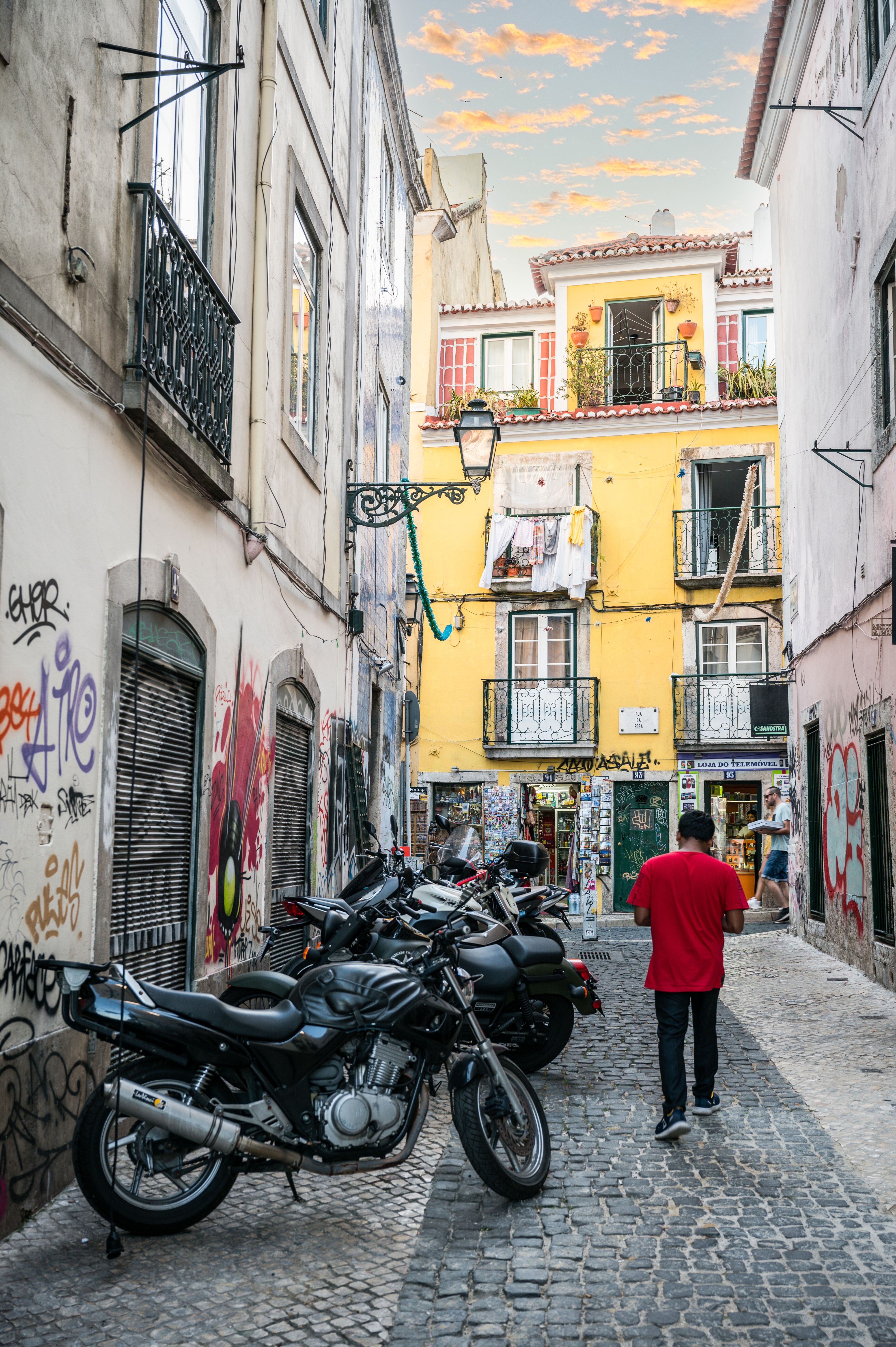 Cobblestone street in Lisbon Portugal with man walking in red shirt and yellow building