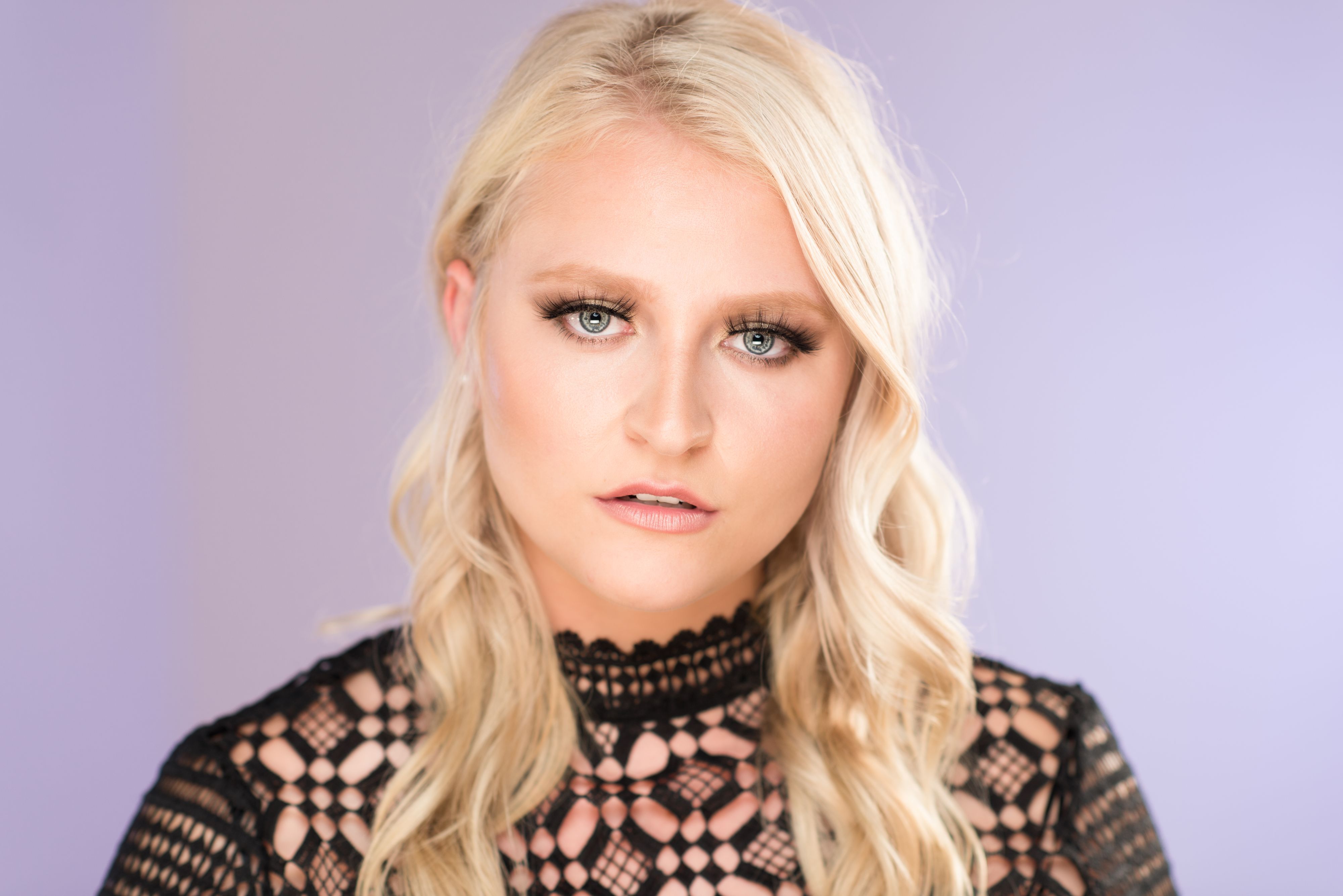 Beauty shot of blonde model wearing black lace on blue background