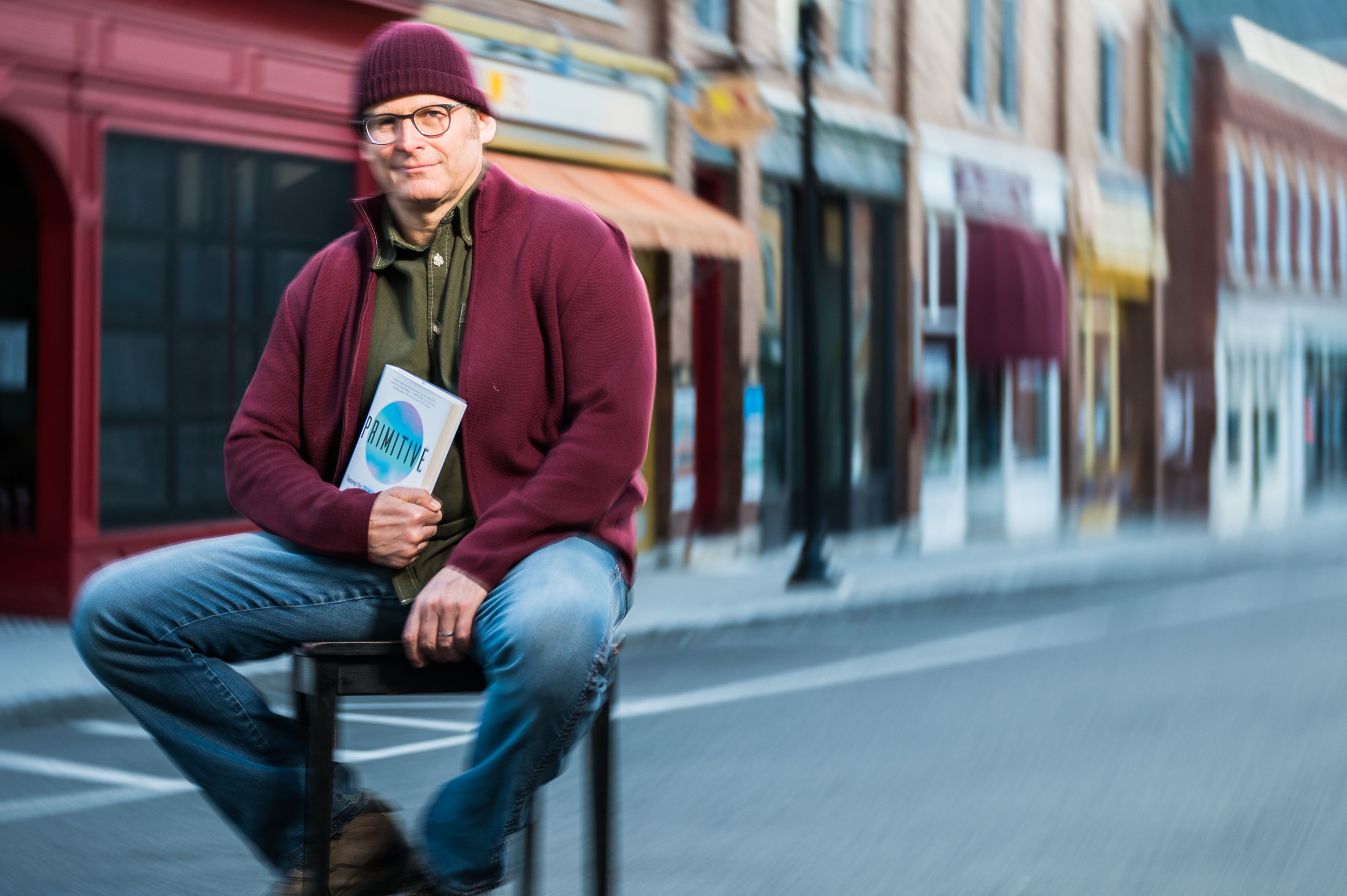 Author sits on Railroad Street in Great Barrington, MA with his book