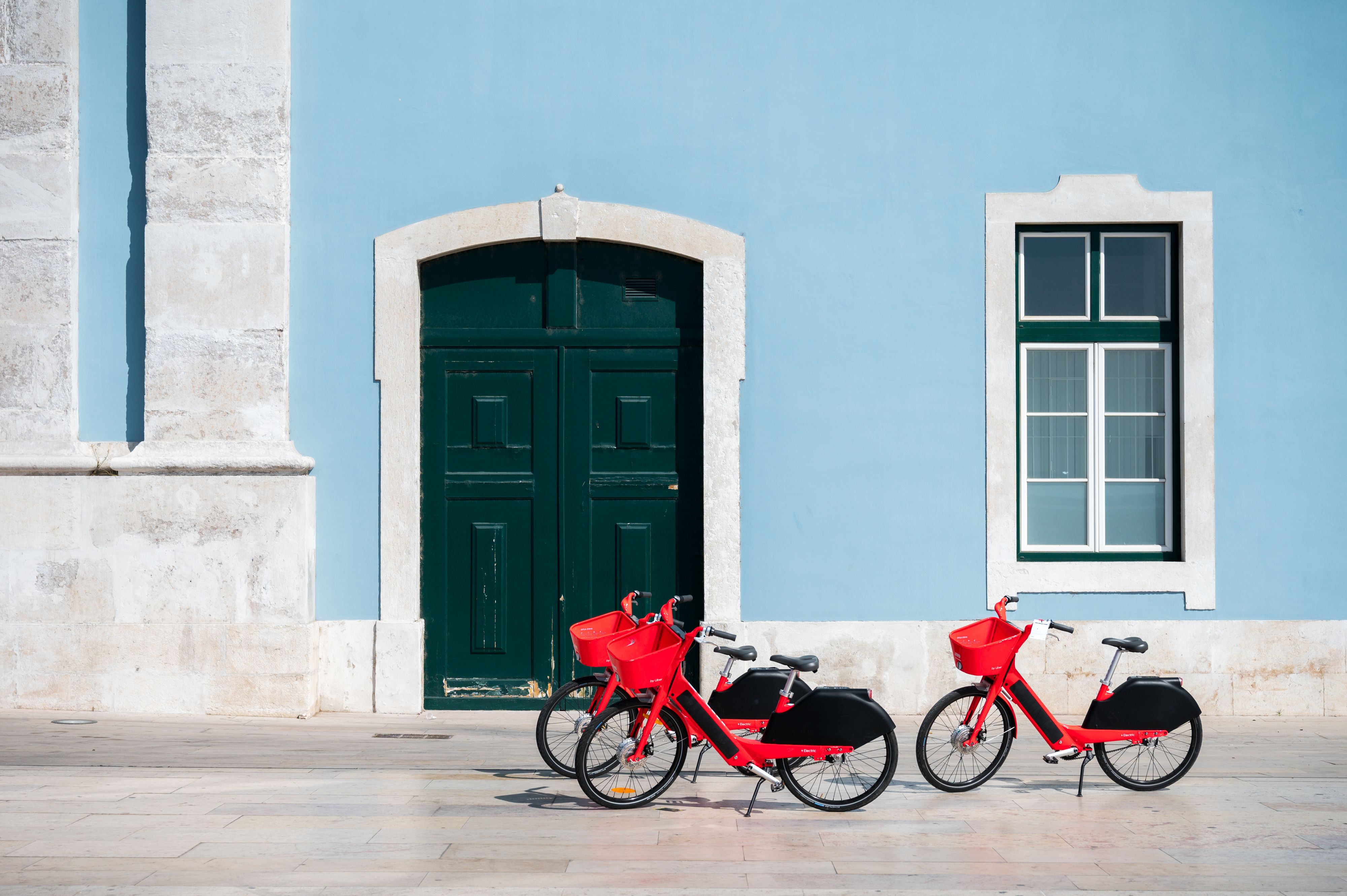Three red bicycles in Lisbon Portugal parked against blue wall