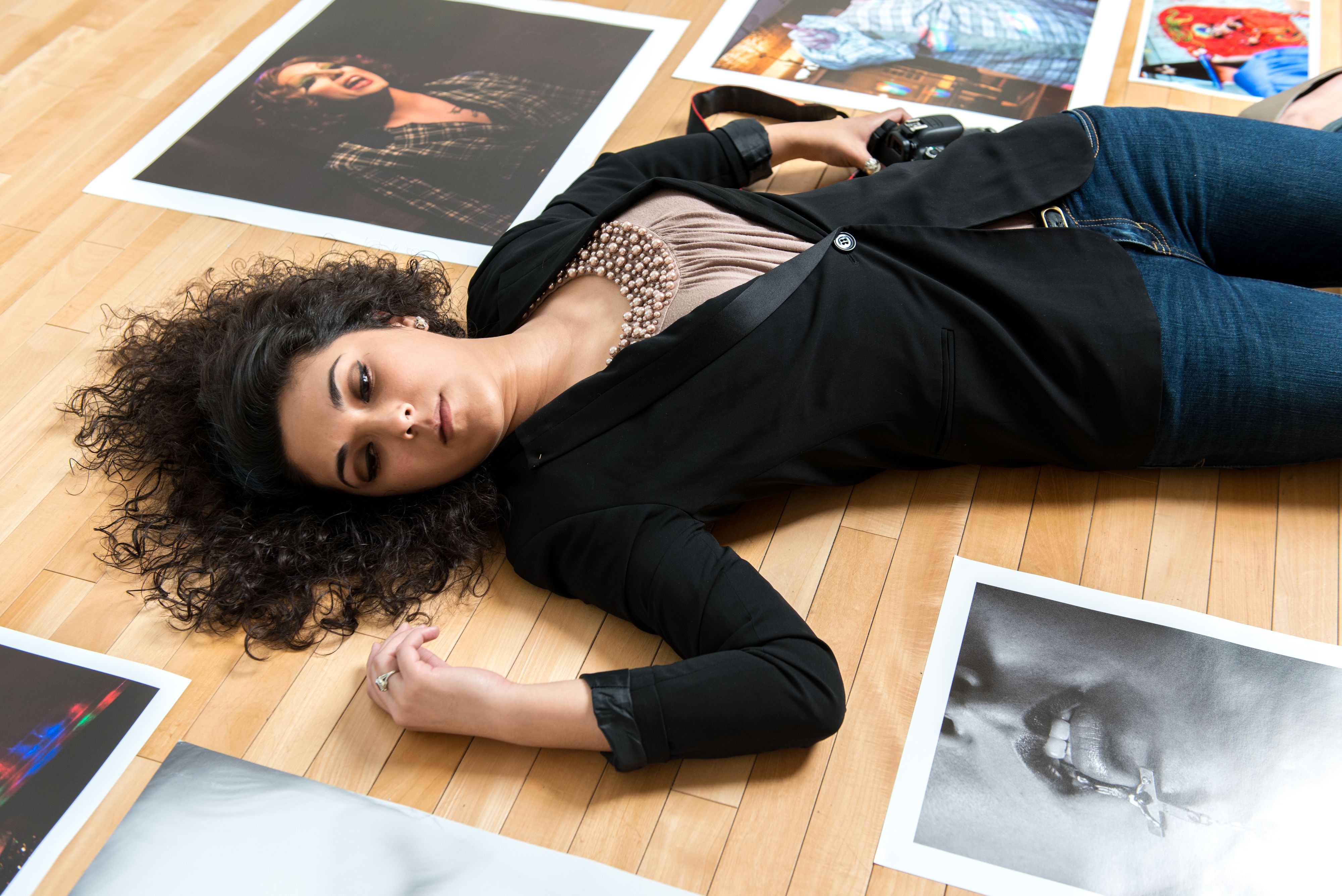 Female photography student lying on back surrounded by her images