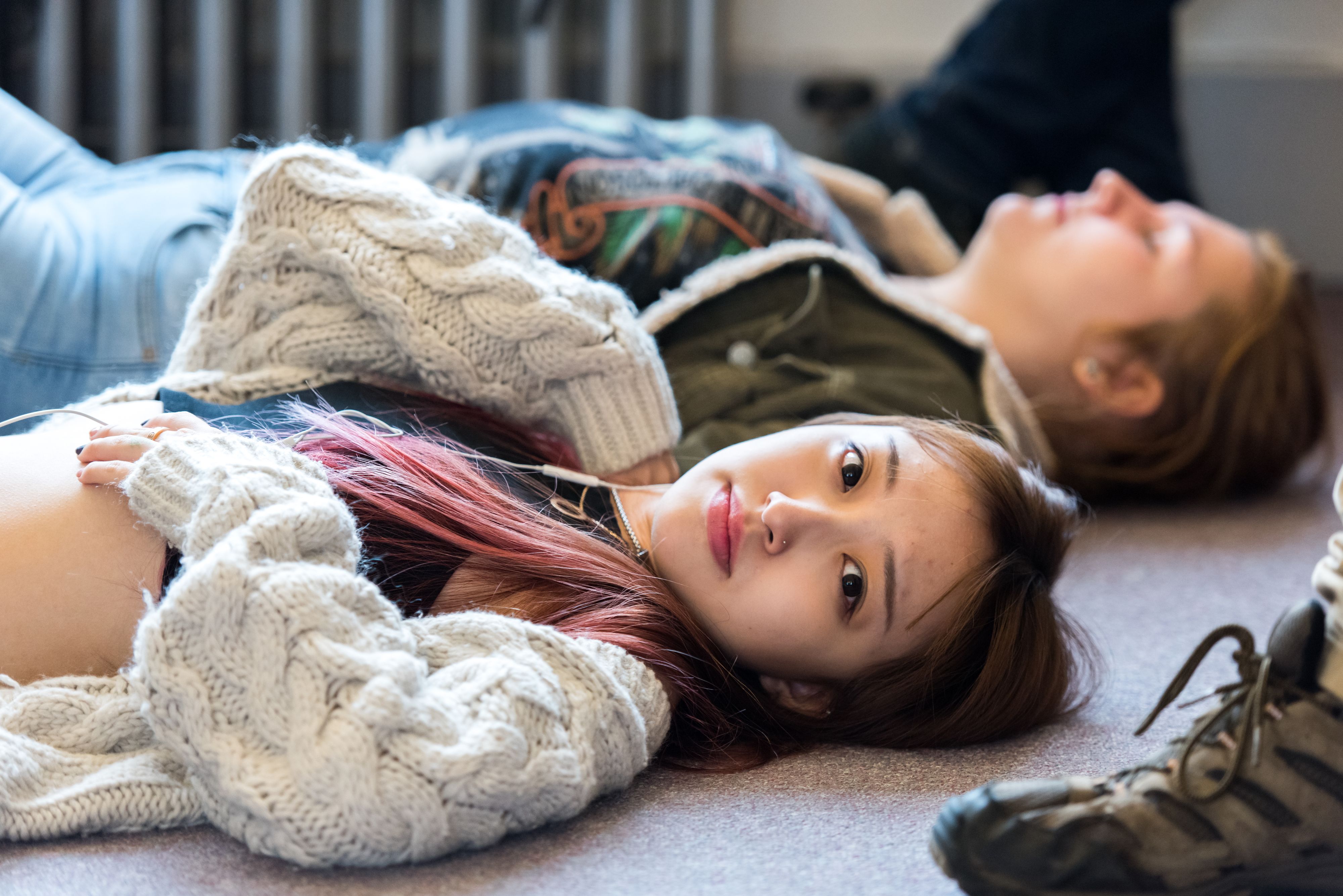 Asian American high school student lying on back looks at camera
