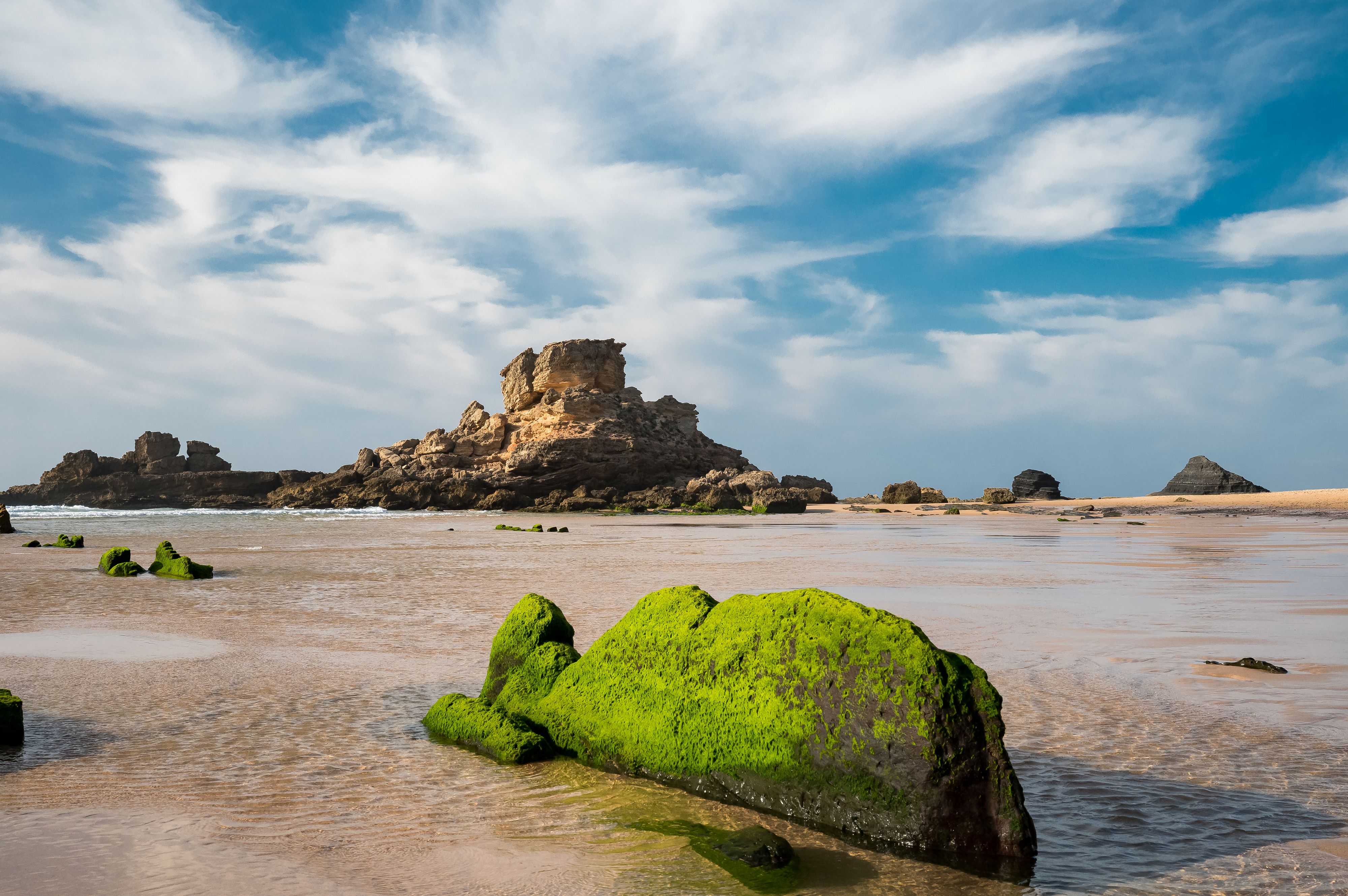 Rocky Portugal beach with mossy rock in foreground