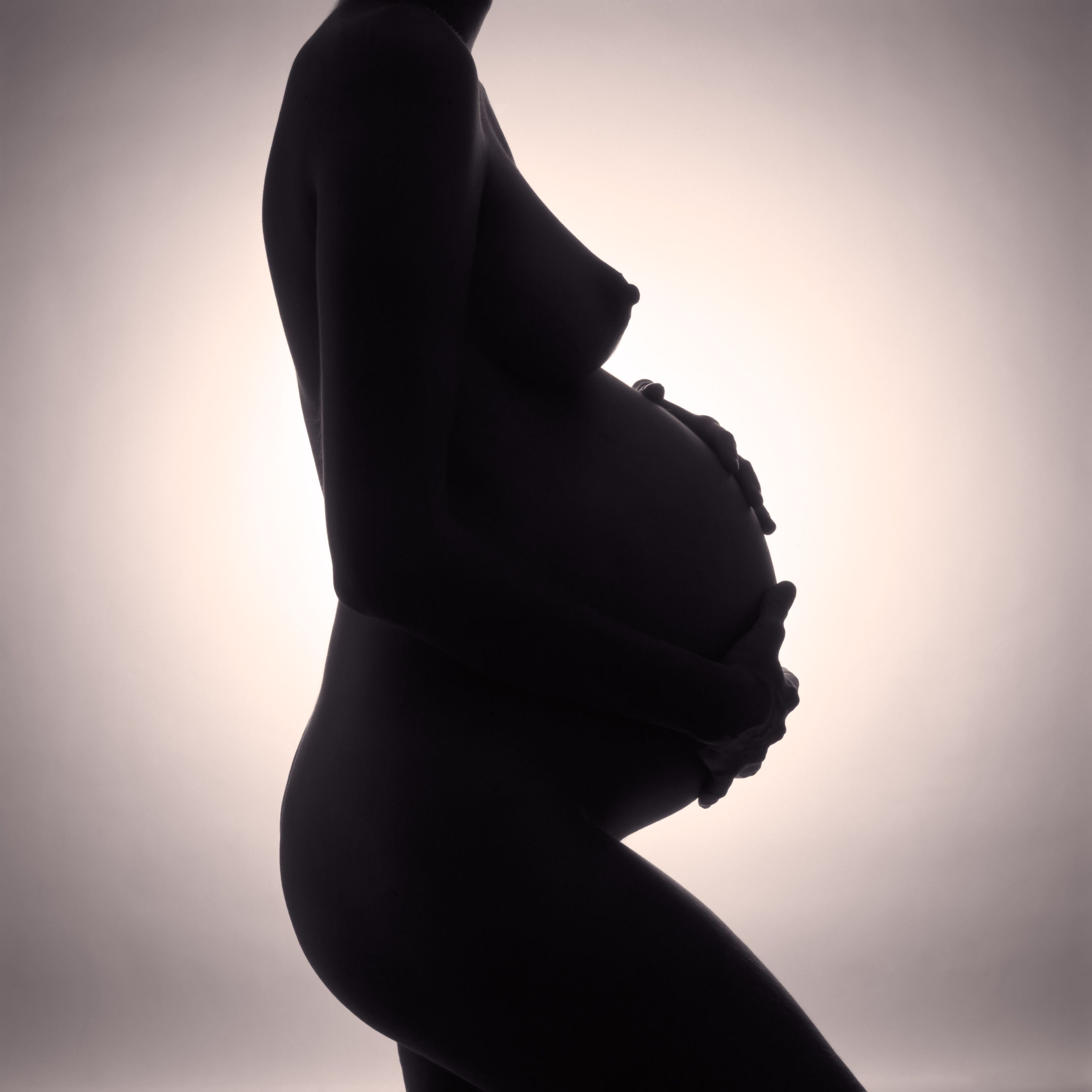 B&W silhouette of pregnant woman with hands on stomach