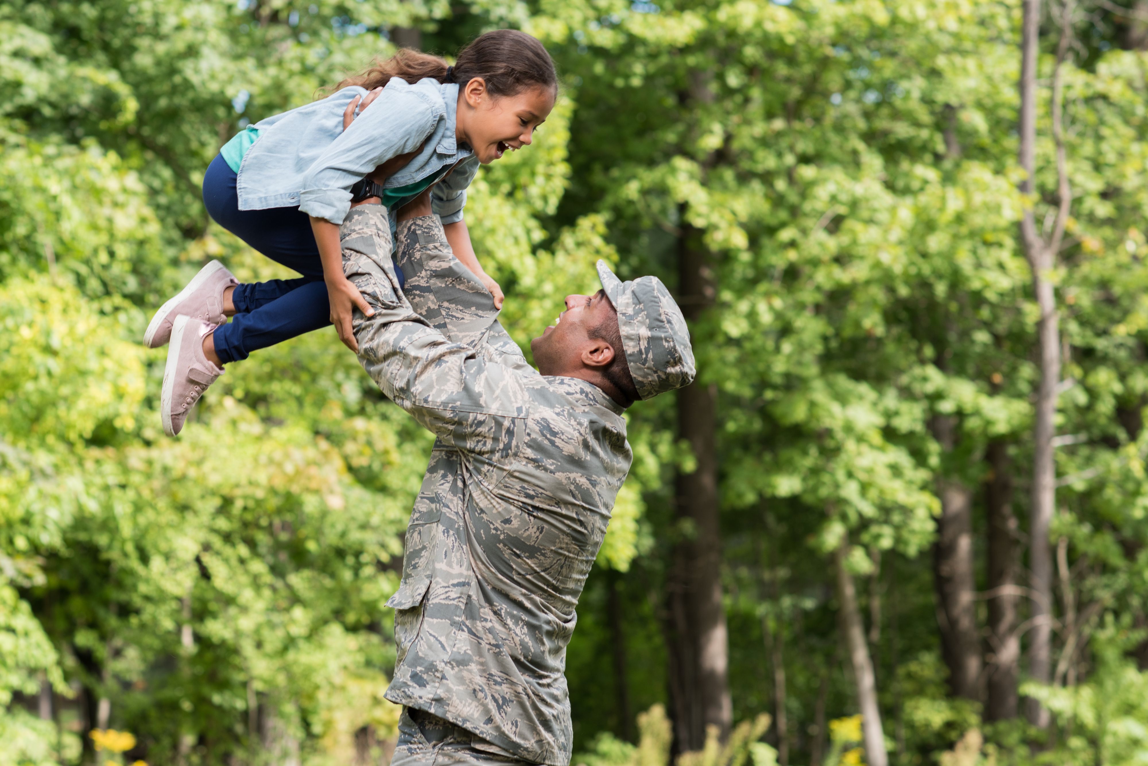 Soldier lifts daughter into air in outdoor lifestyle