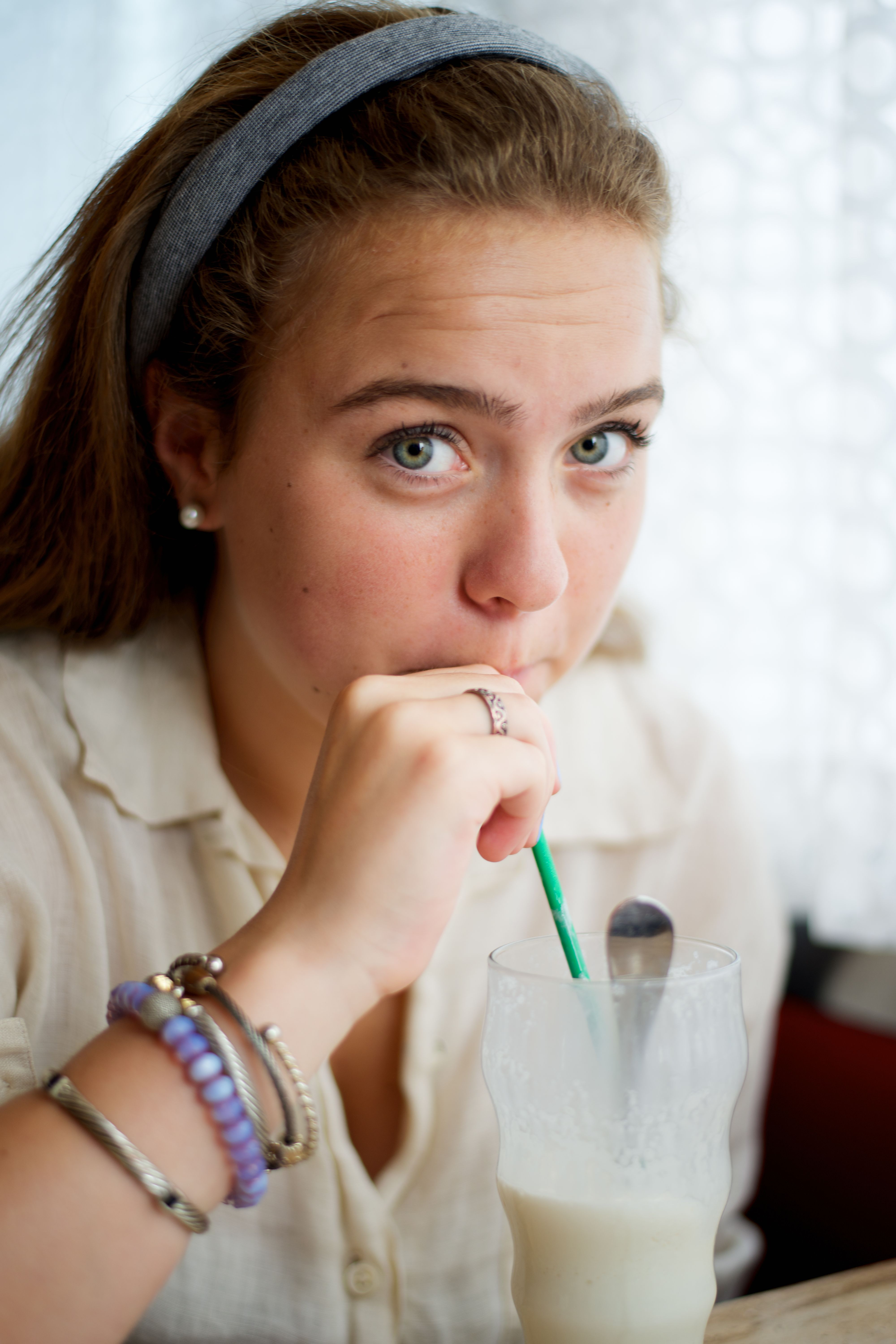 Young woman with hair band and bracelets enjoys milkshake