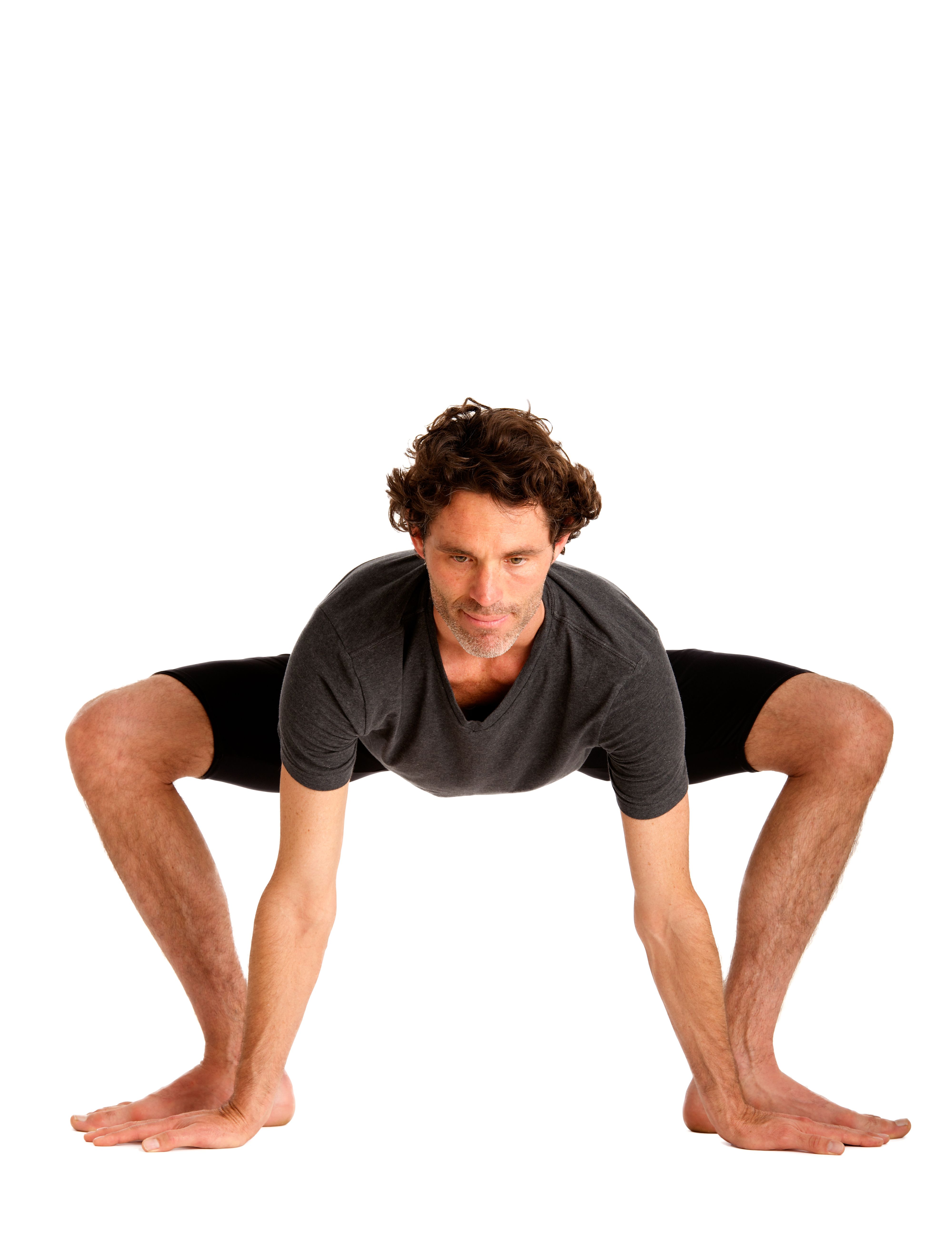Male in studio doing yoga pose with hands and feet on ground