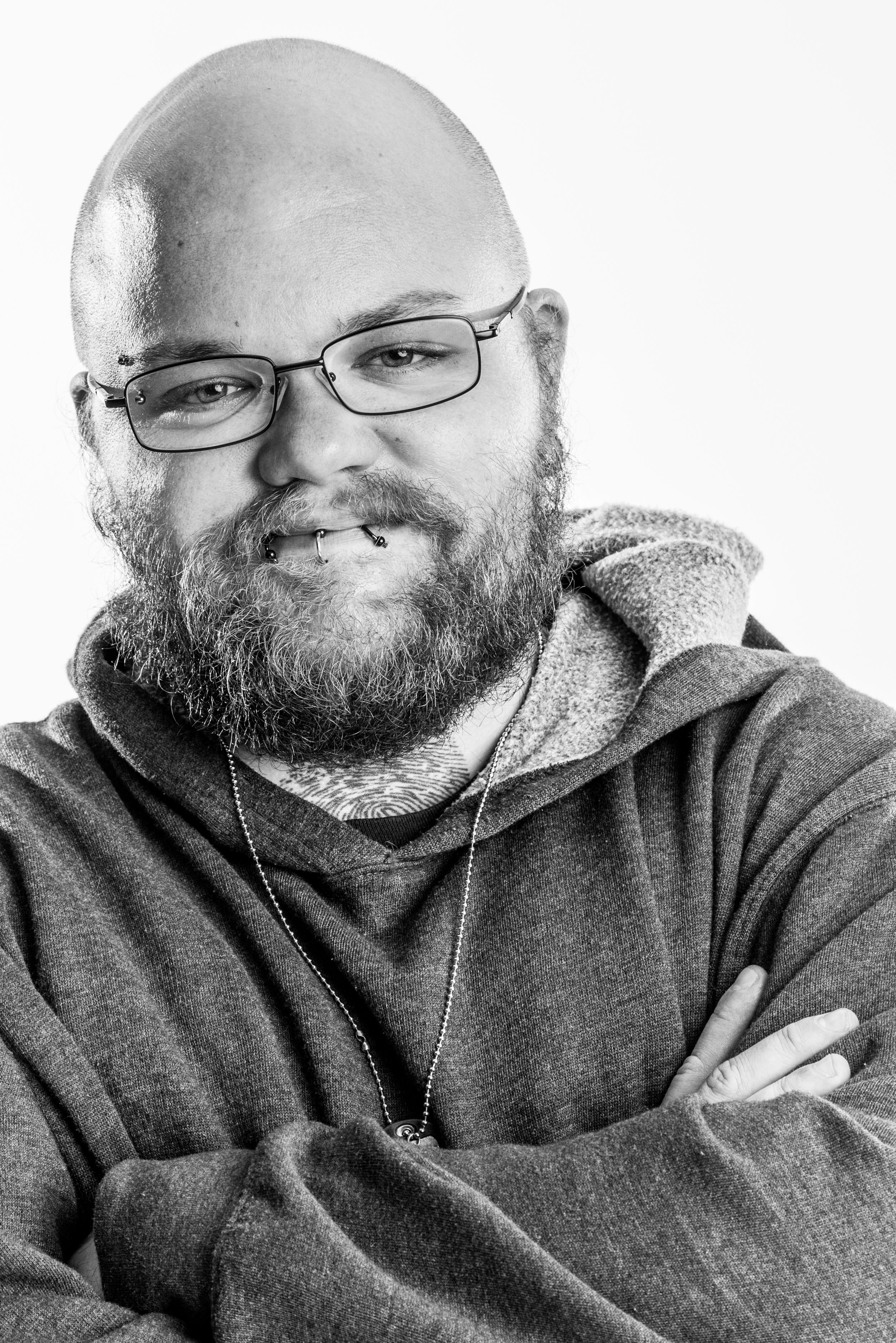 B&W portrait of bald man with beard on white background in studio