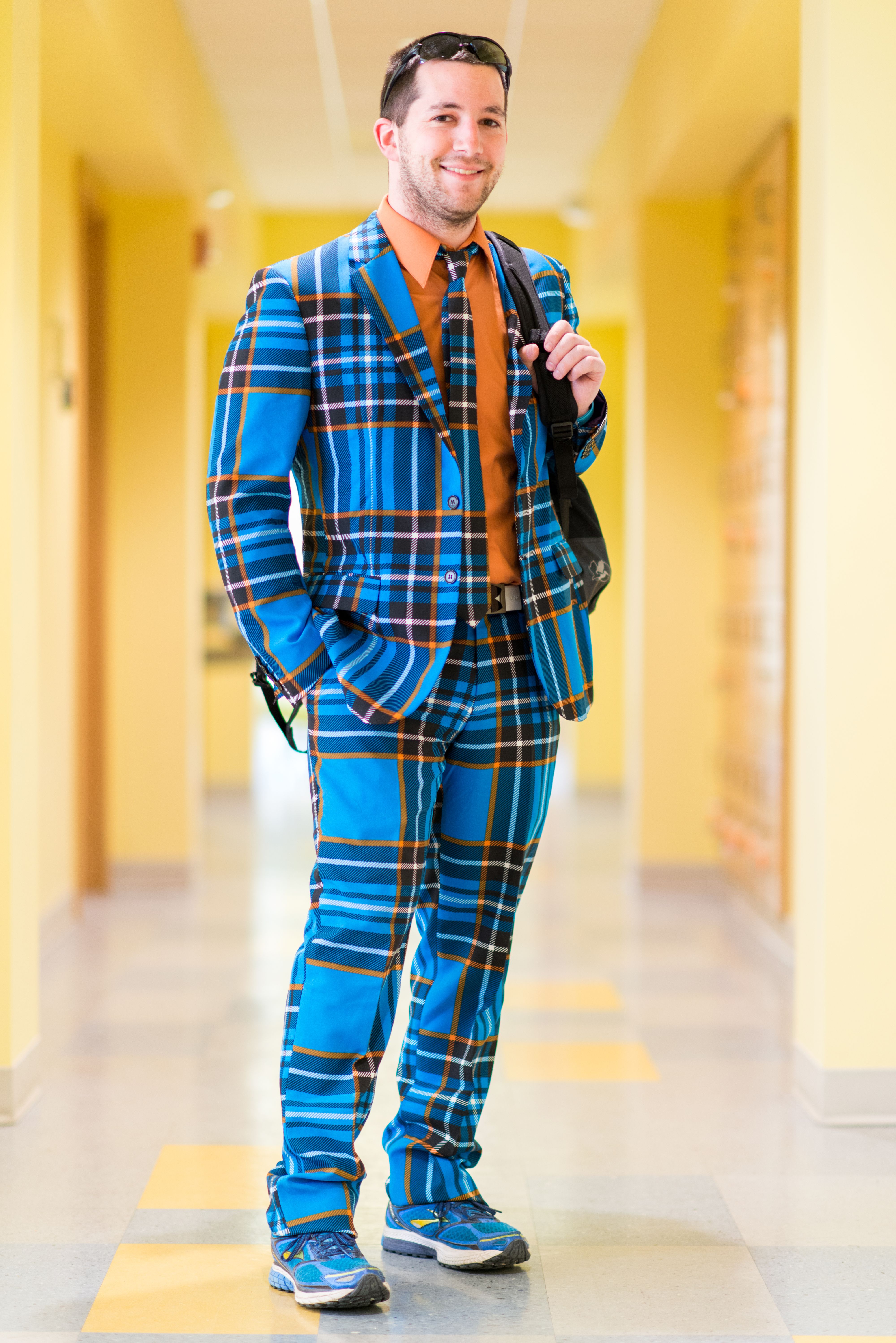 Portrait of male college student in hallway wearing blue plaid suit holding backpack