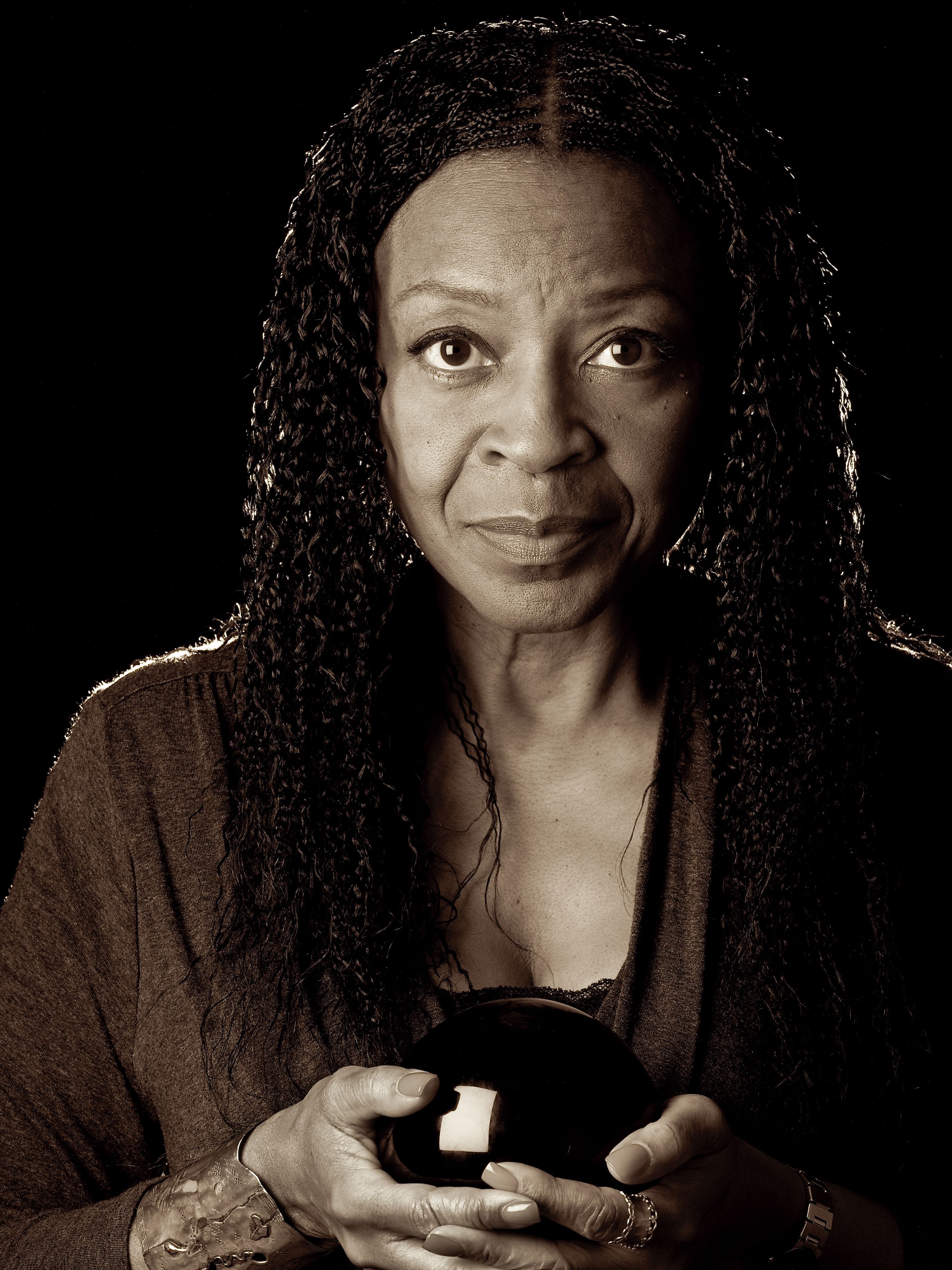 B&W studio portrait on black of African American Woman holding black orb 