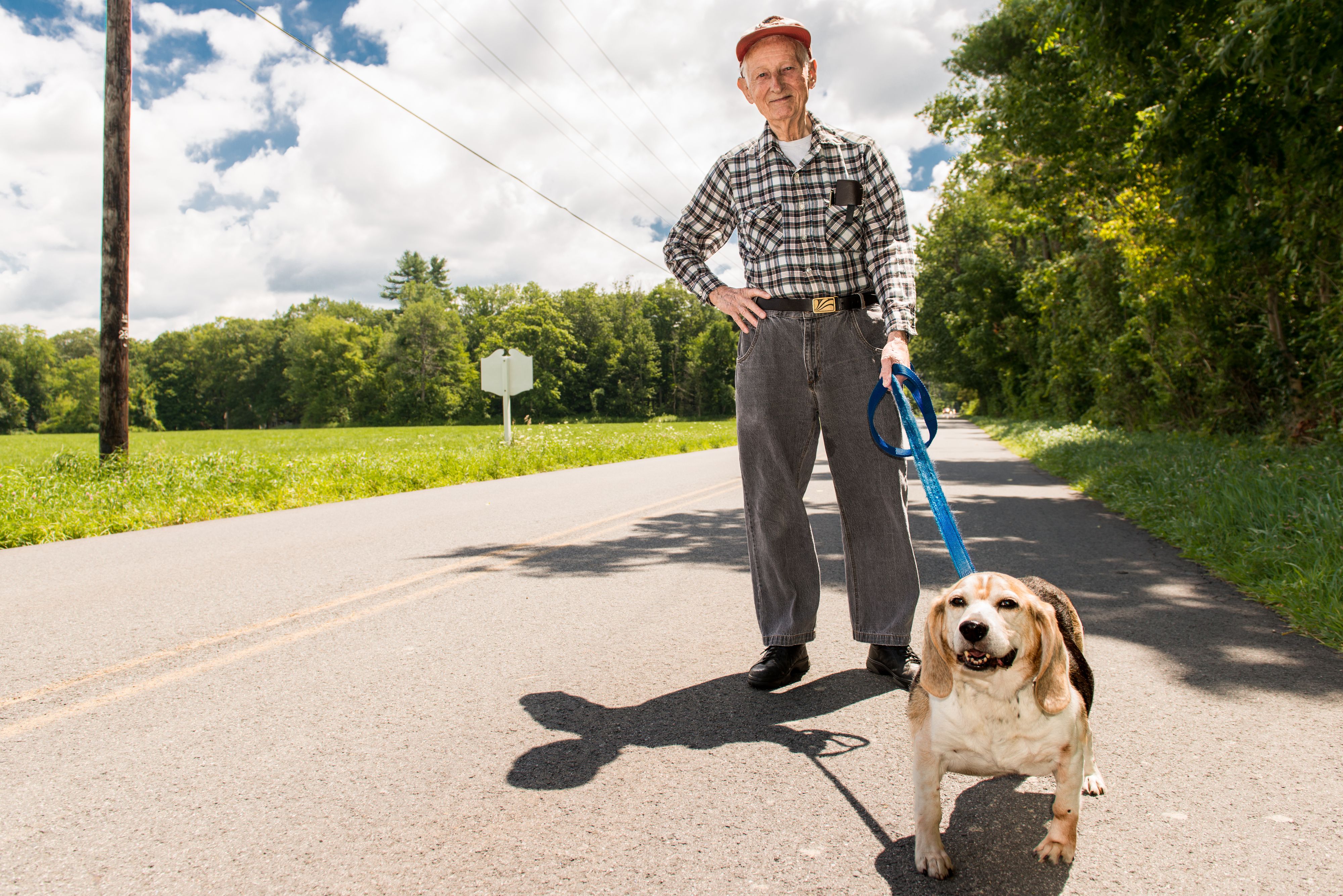 Old man in street in cap walking dog