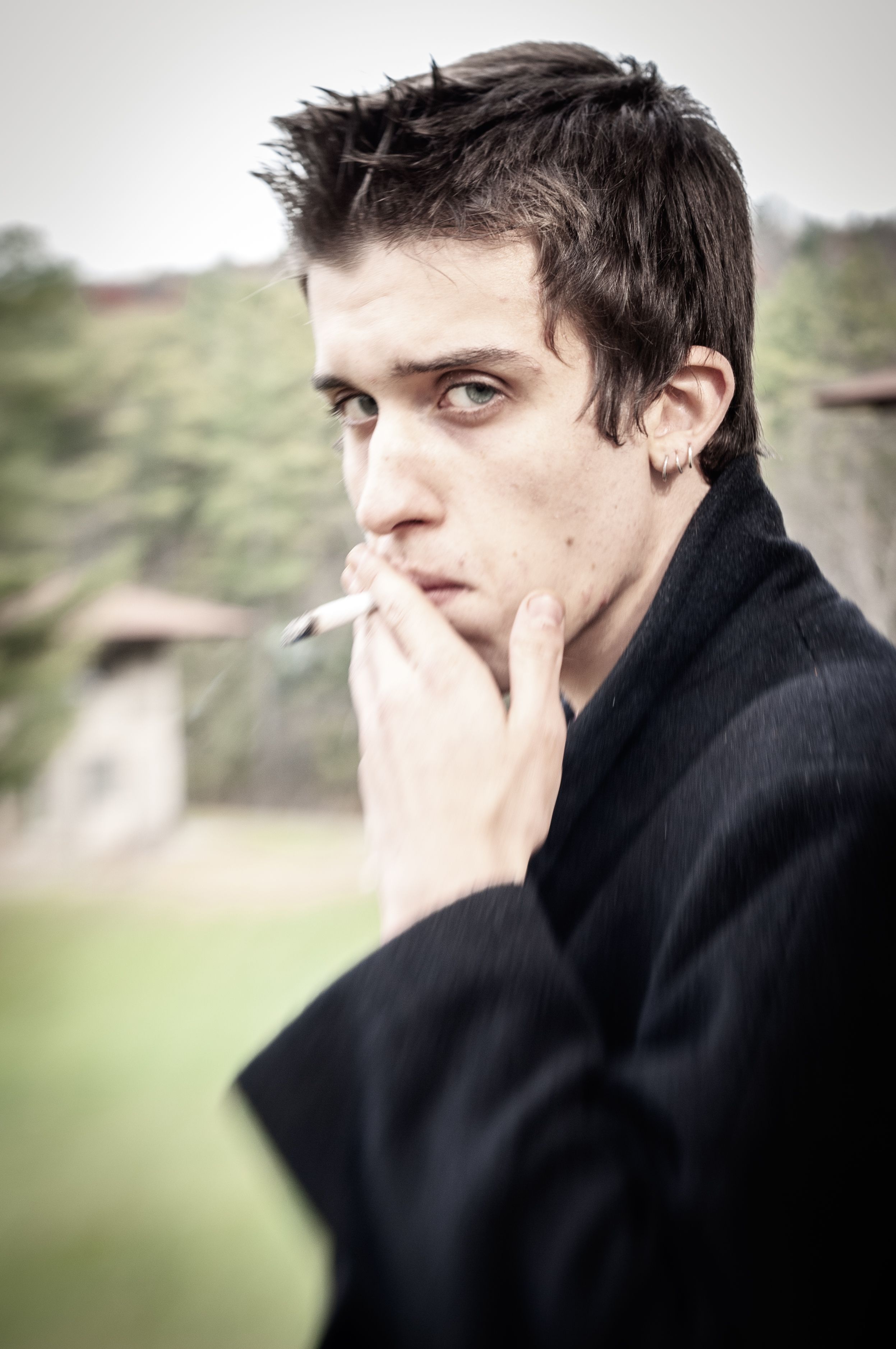 Young man in dark wool coat smoking cigarette
