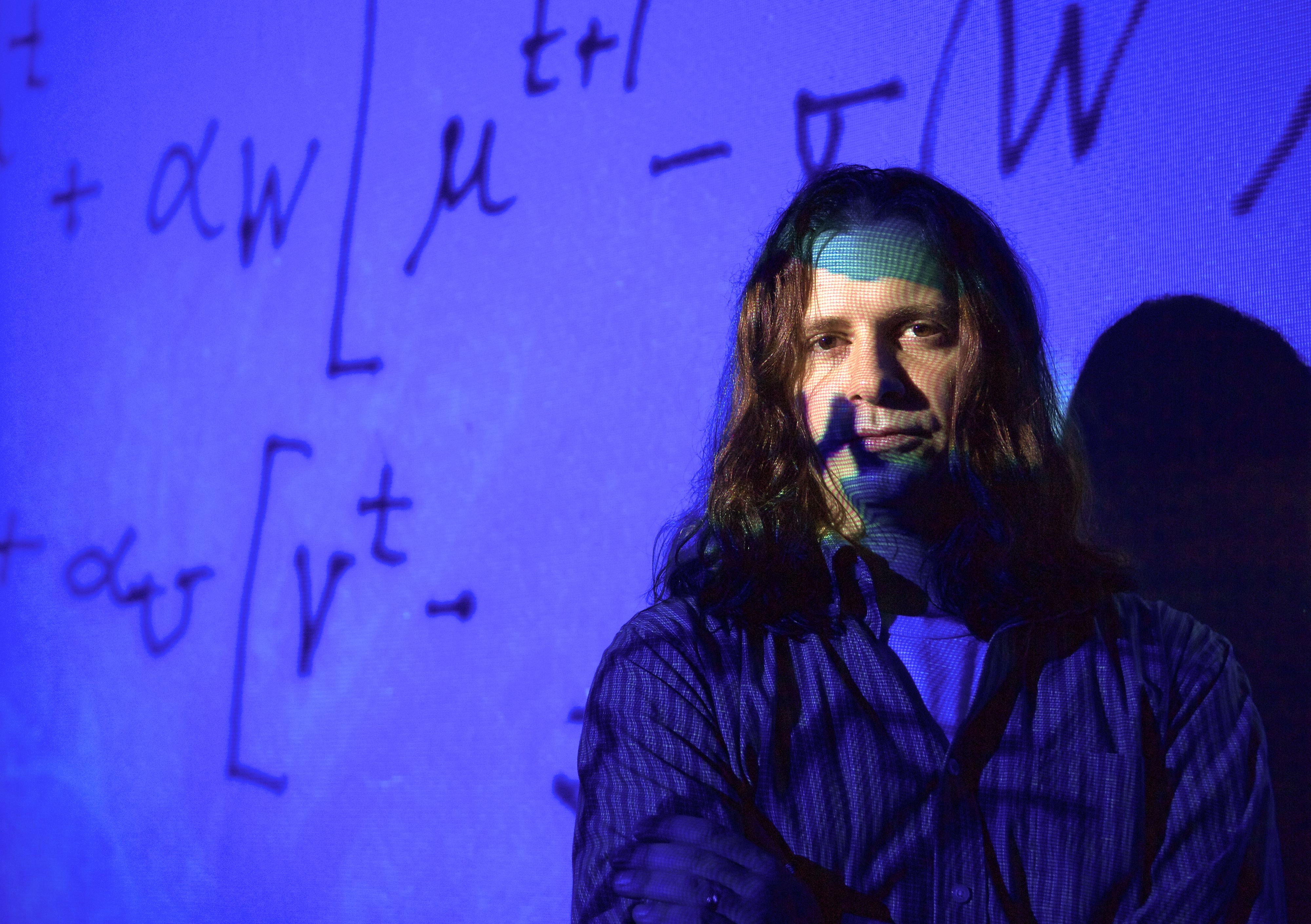 Portrait of physics professor on projected blue background with mathematical formulas
