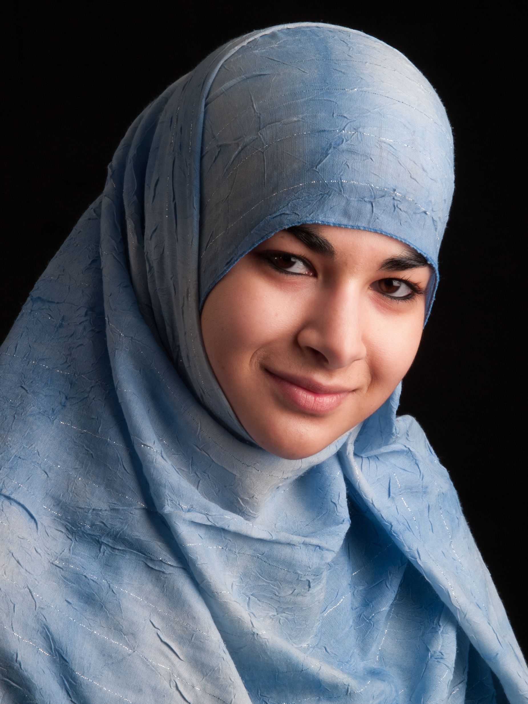 Studio portrait of young woman in Hijab on black background