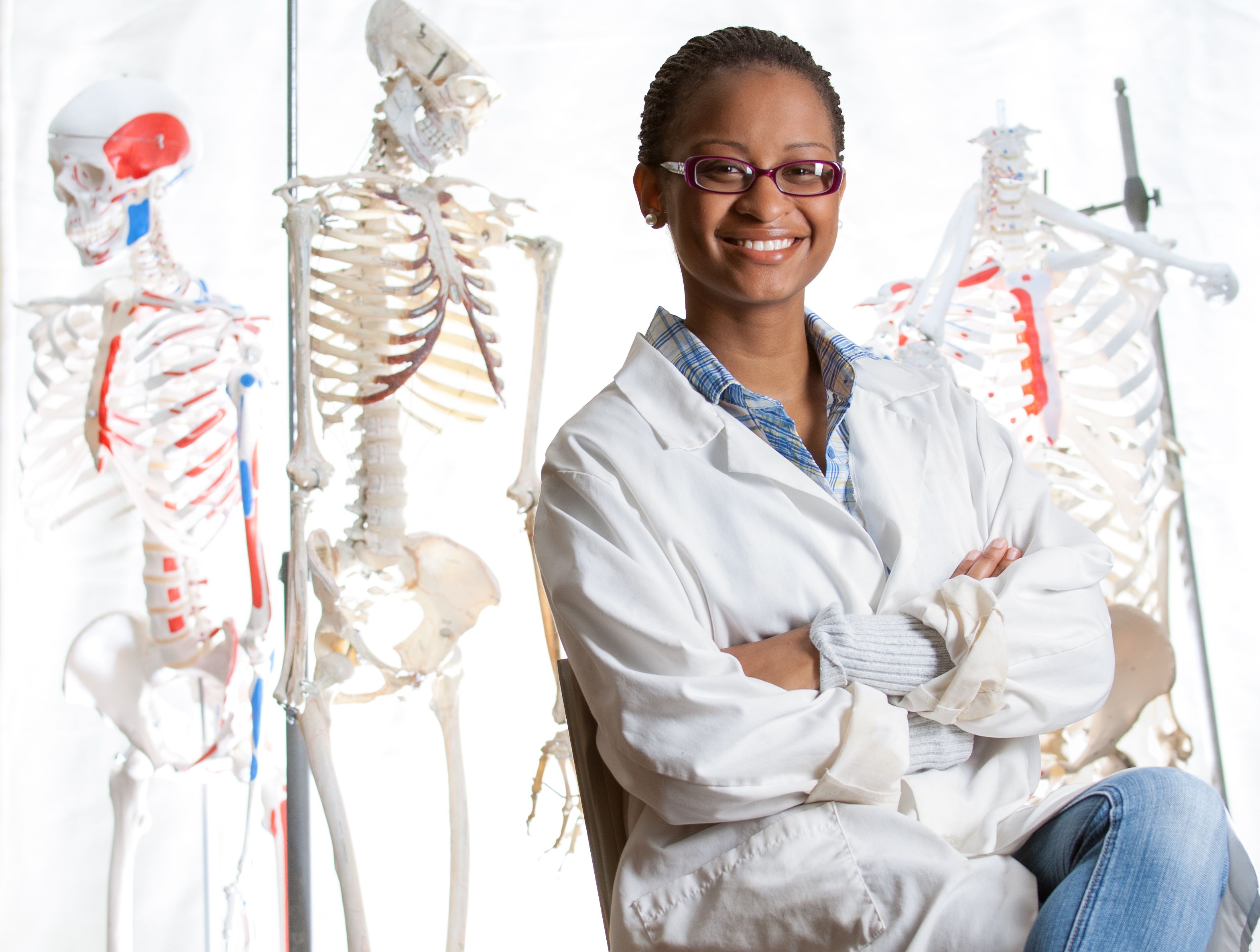 Portrait of African American medical student with skeletons in background
