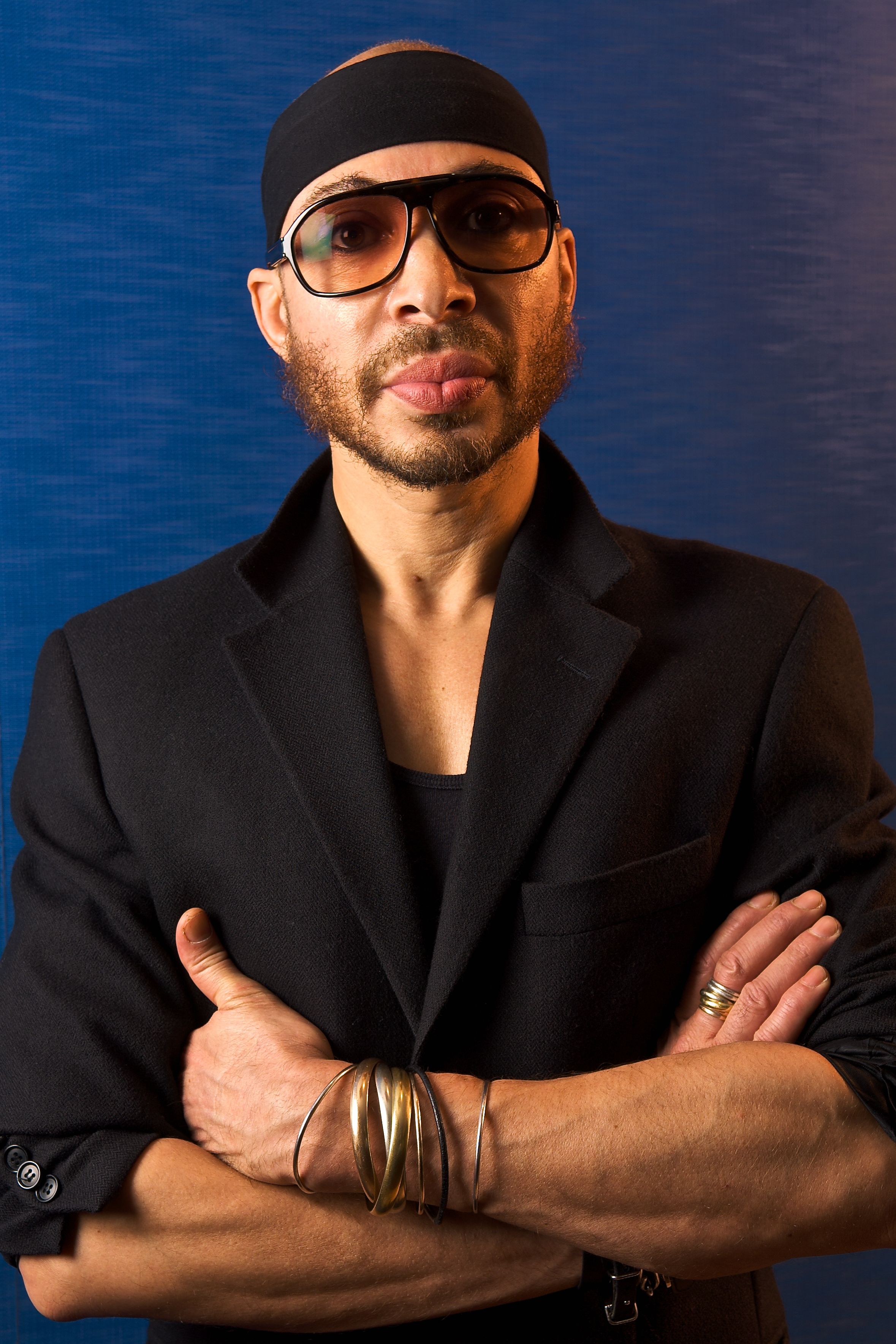 Portrait of an African American man on blue background with sunglasses and bracelets