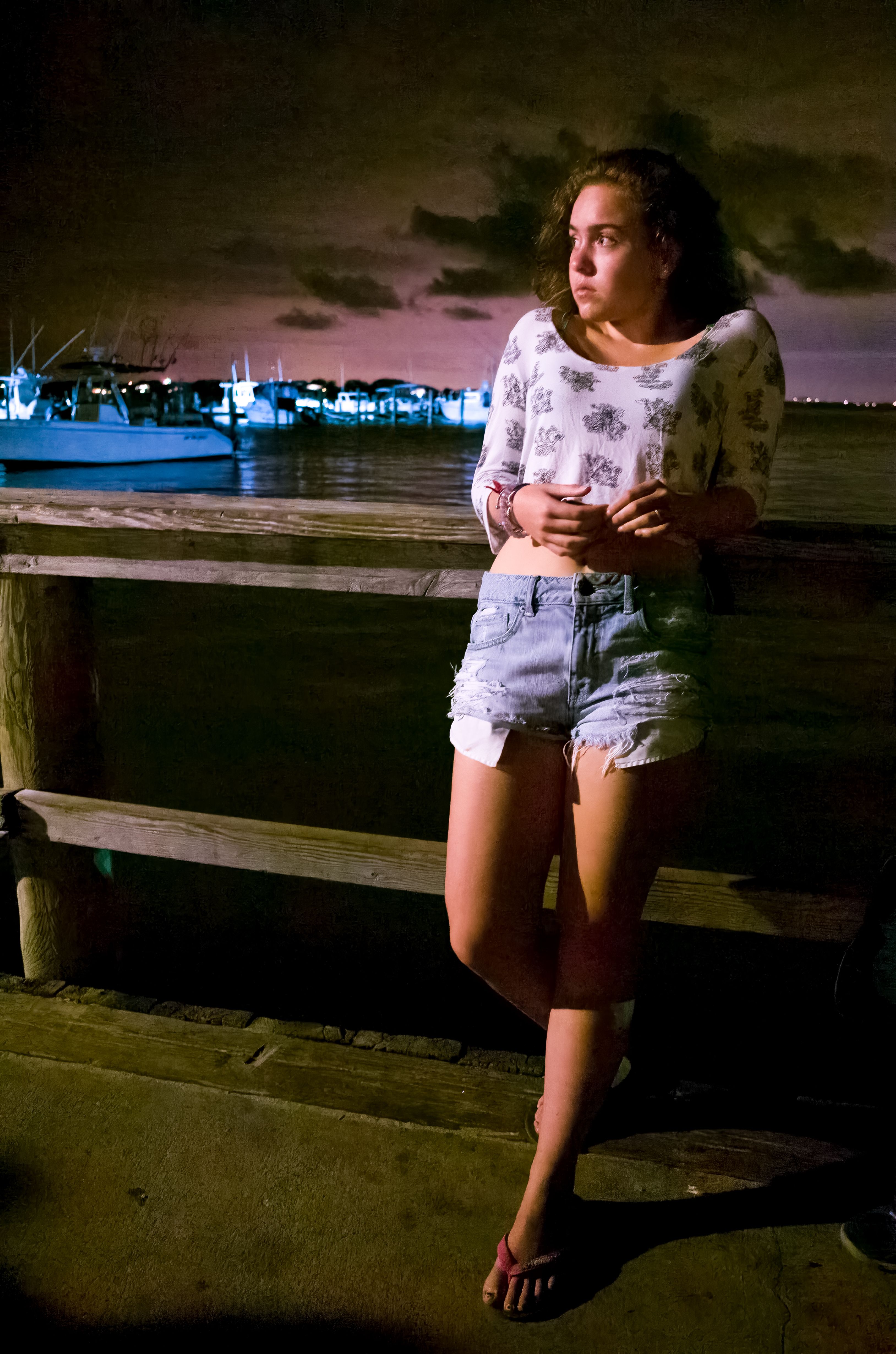 Teenage girl stands on fence at night in Marina