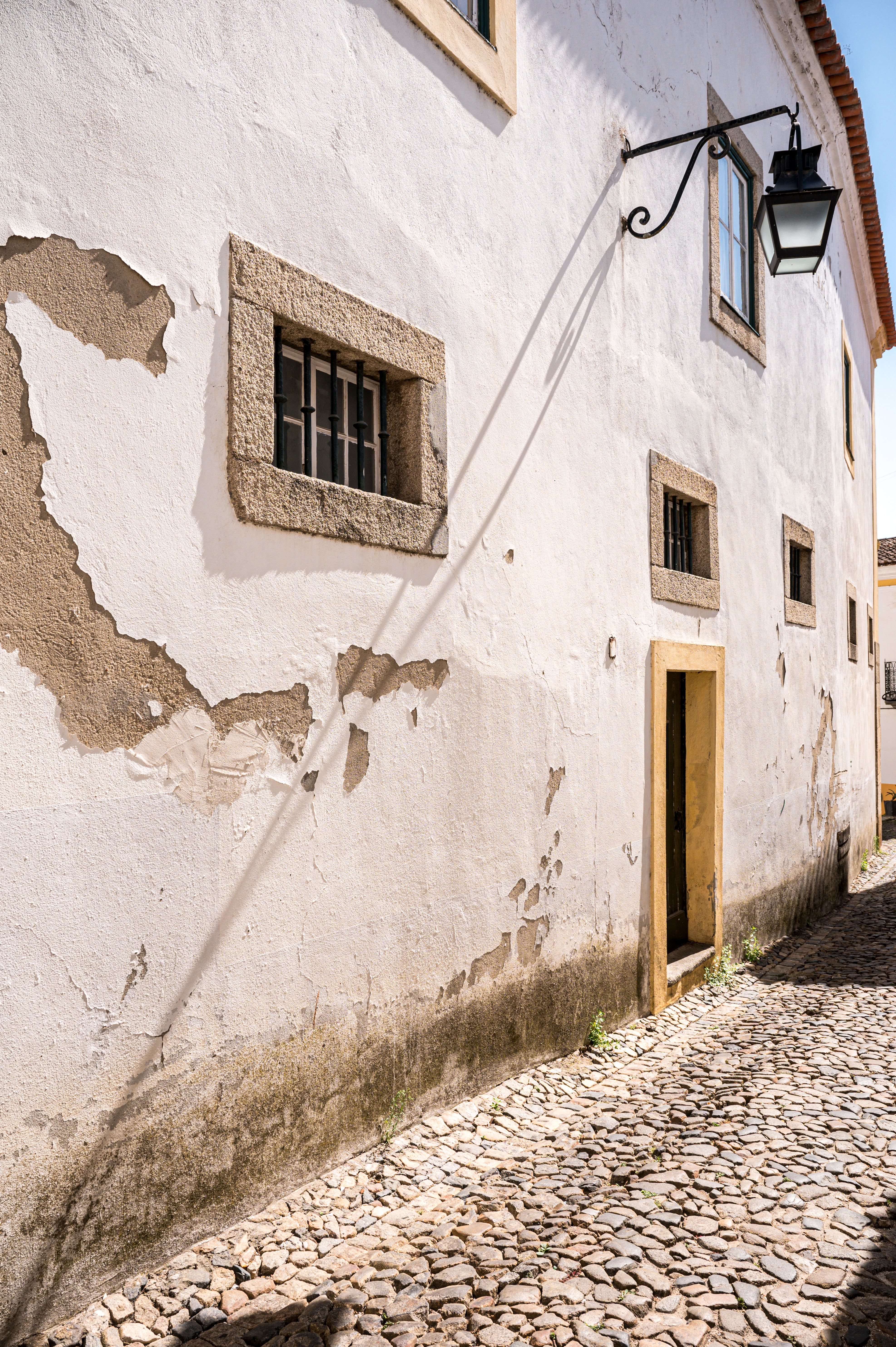 Old cobblestone street in Portugal with yellow doorway and lamp