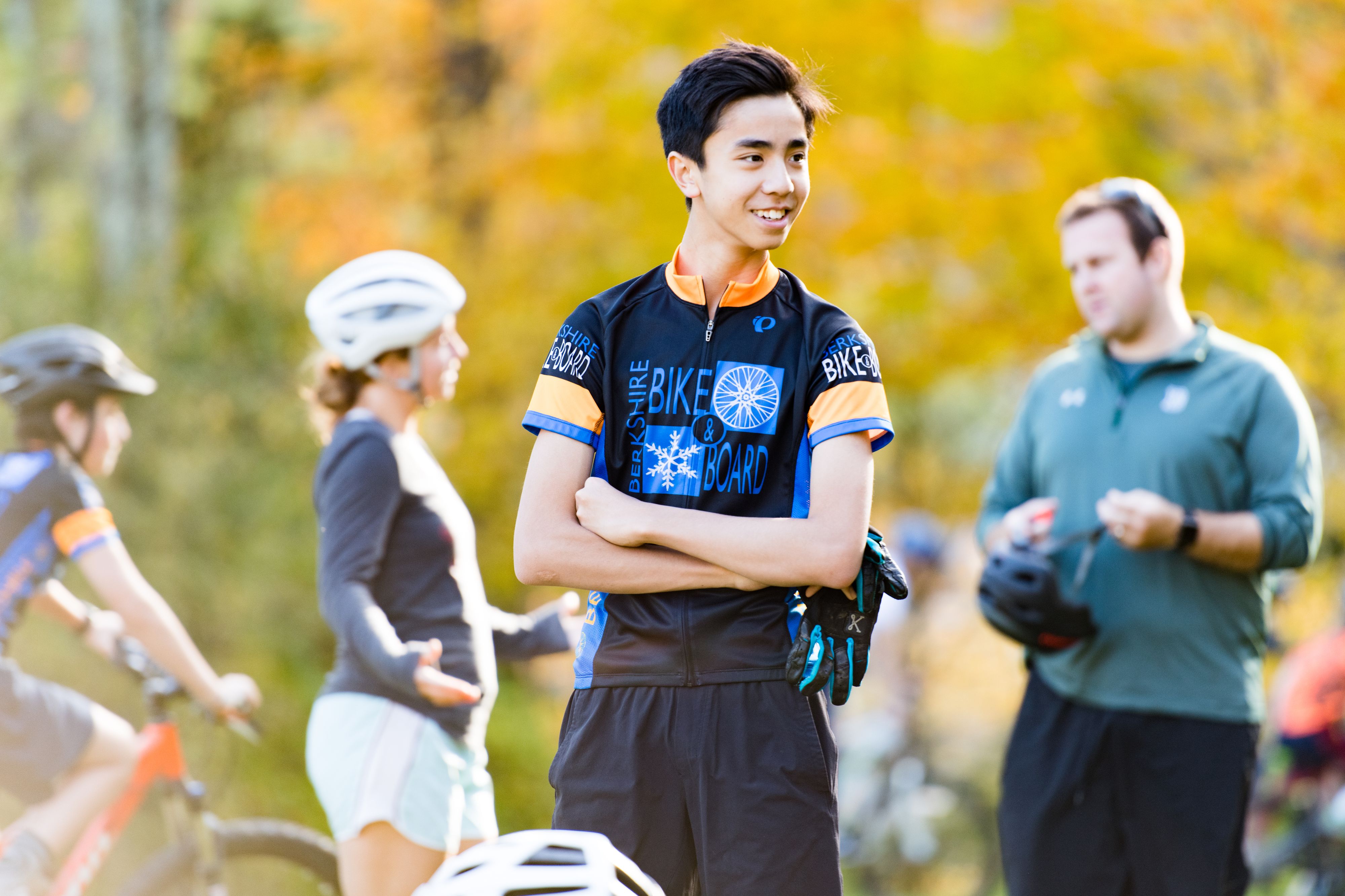 Young smiling mountain bike racer in fall with others in background